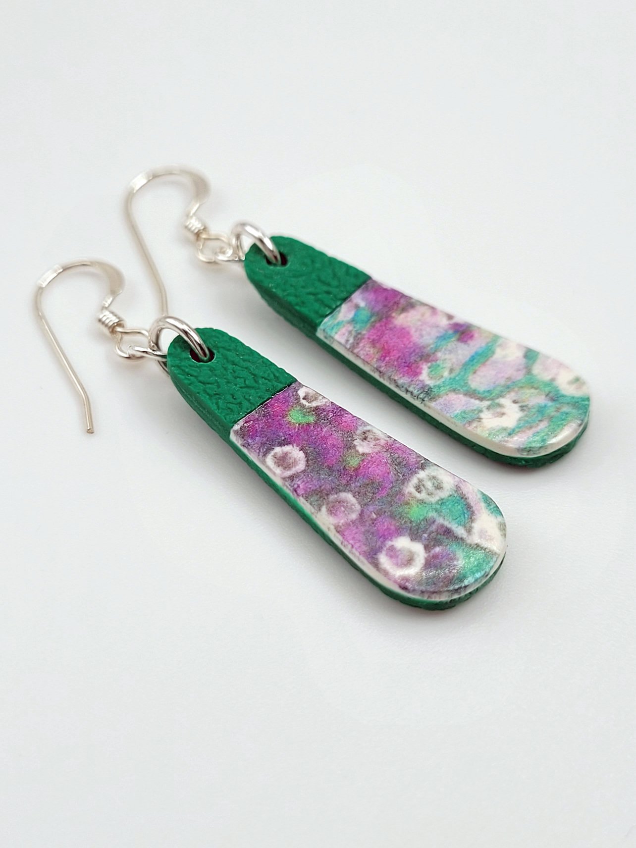 Flat lay of teardrop earrings highlighting their contemporary pastel floral design and elegant shape.