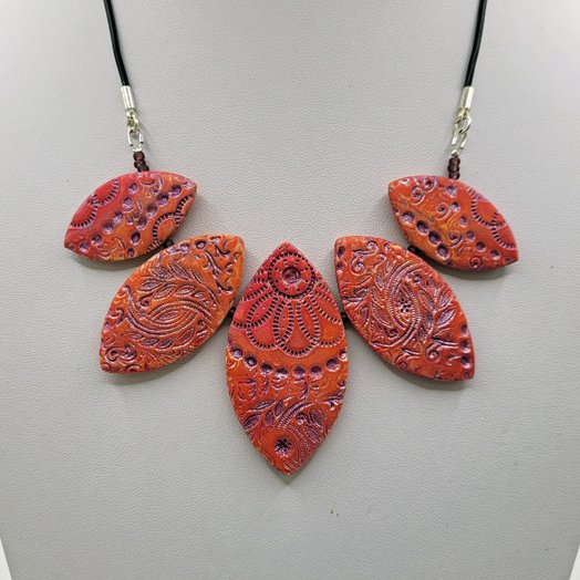 5 petal bead necklace in warm apricot shades with an embossed pattern picked out in metallic mauve paint.