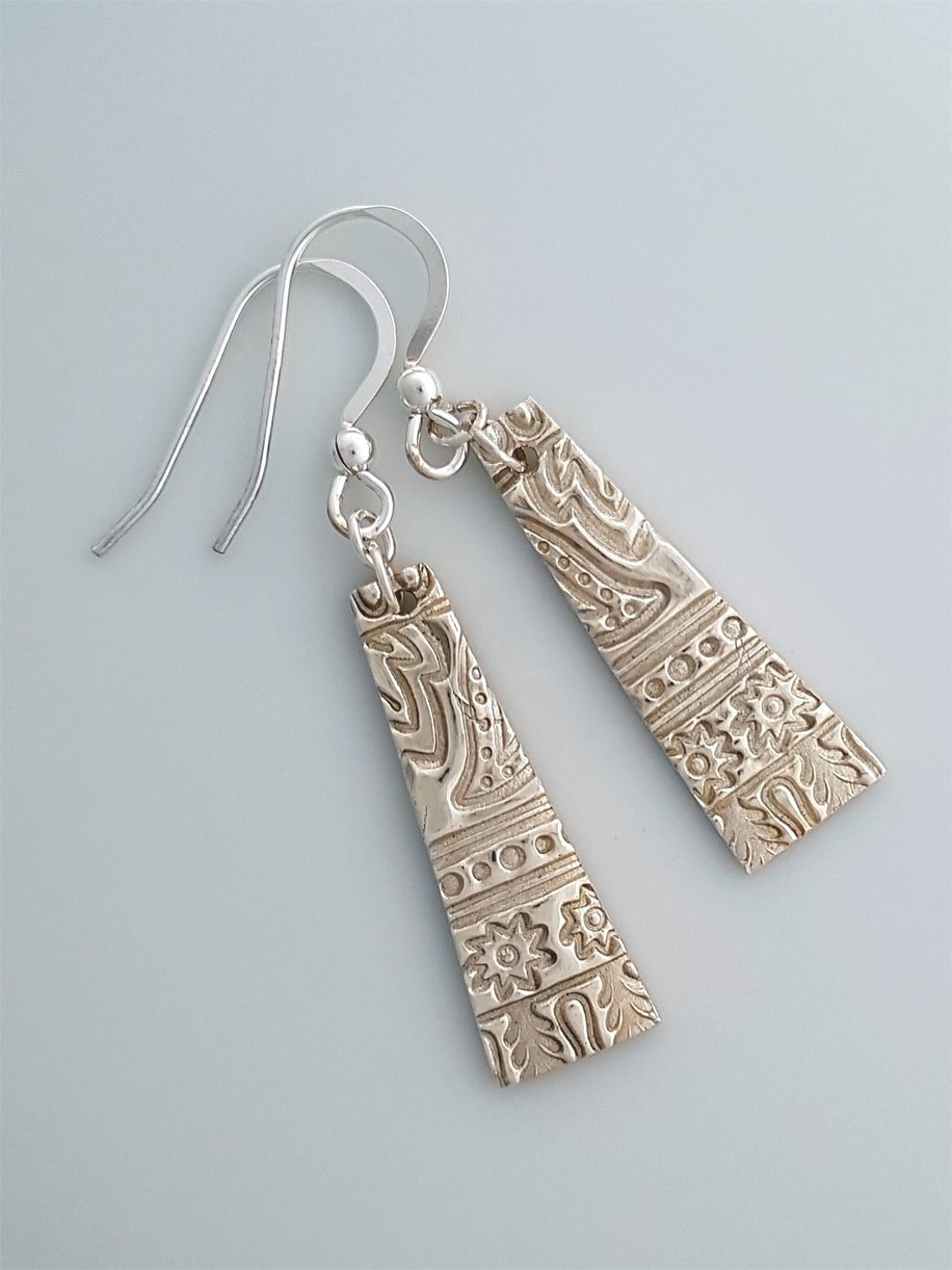 Long trapezoid fine silver earrings embossed with an egyptian style motif.