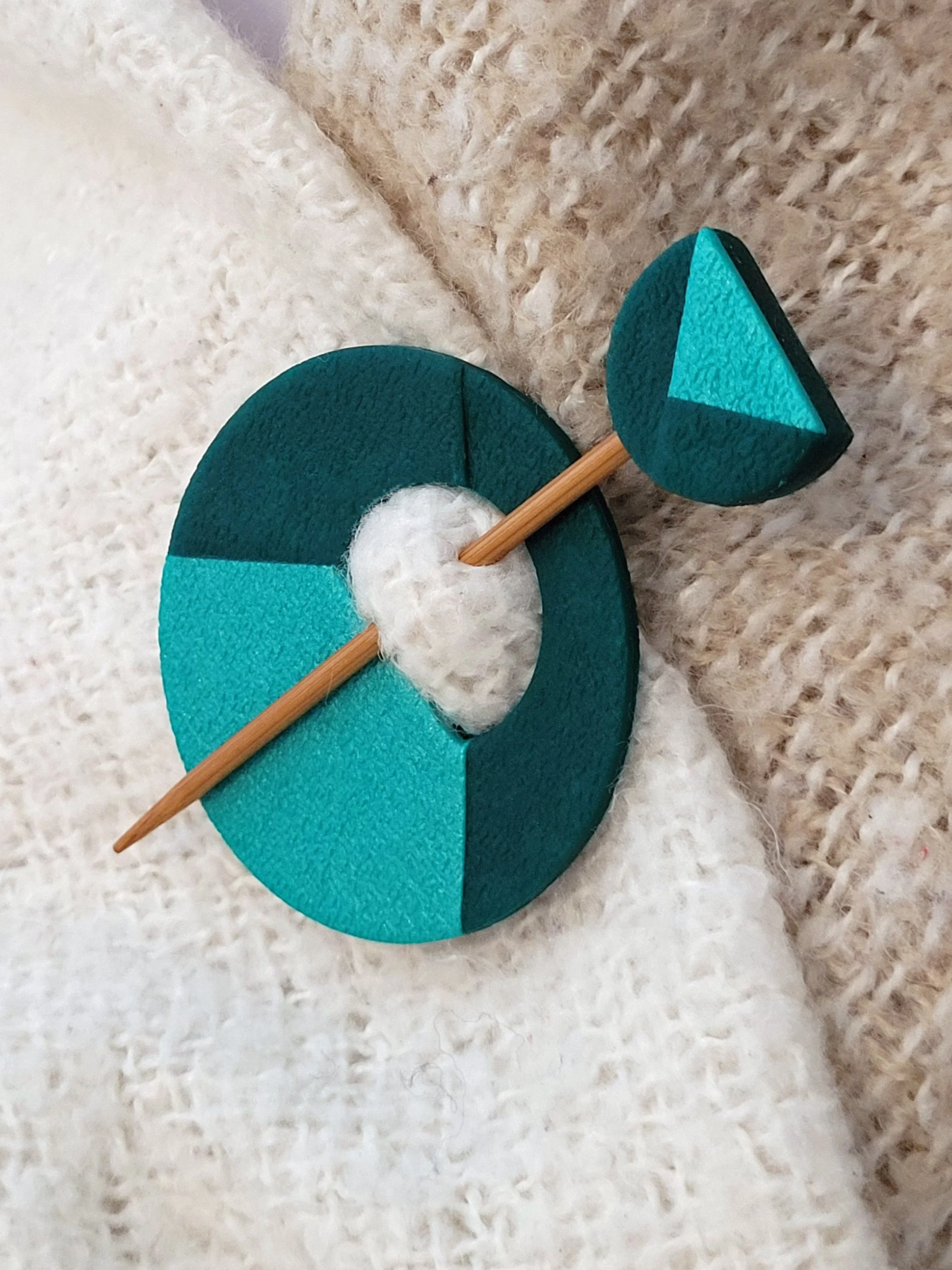 The decorative dark green pin head features a geometric half circle with a pearlescent peacock triangular accent.