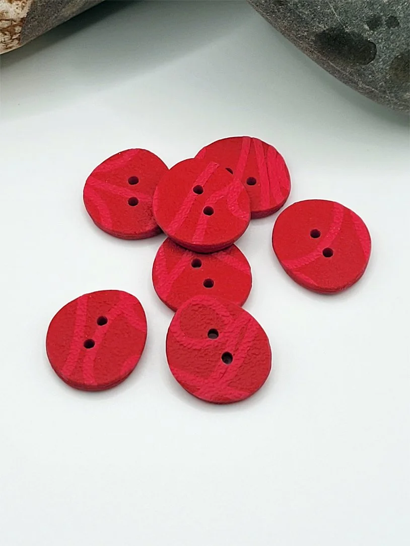 Seven, small size, unique polymer clay buttons with a rich pink linear pattern on a red background.