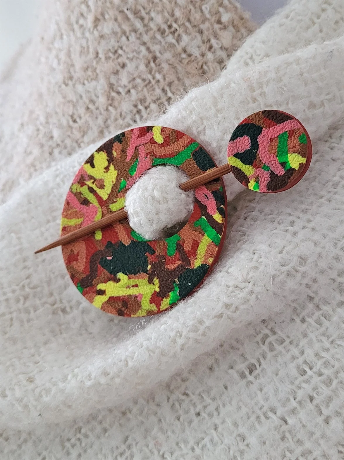 Terracotta Ticker Tape circular Pin shown from the right edge, pinned to a cream shawl.