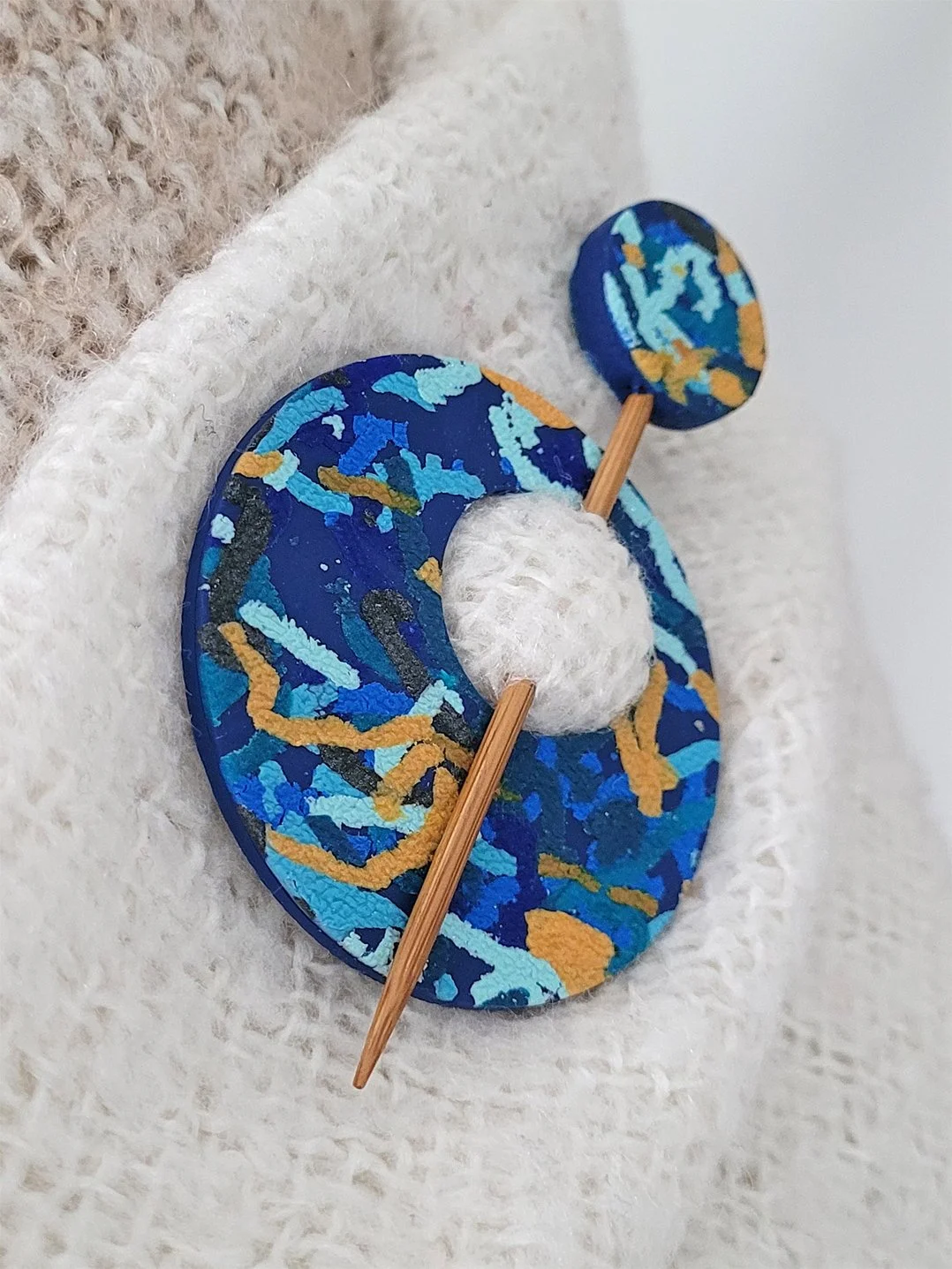 Blue Ticker Tape polymer clay Shawl Pin shown from the left edge, pinned to a cream and brown shawl.