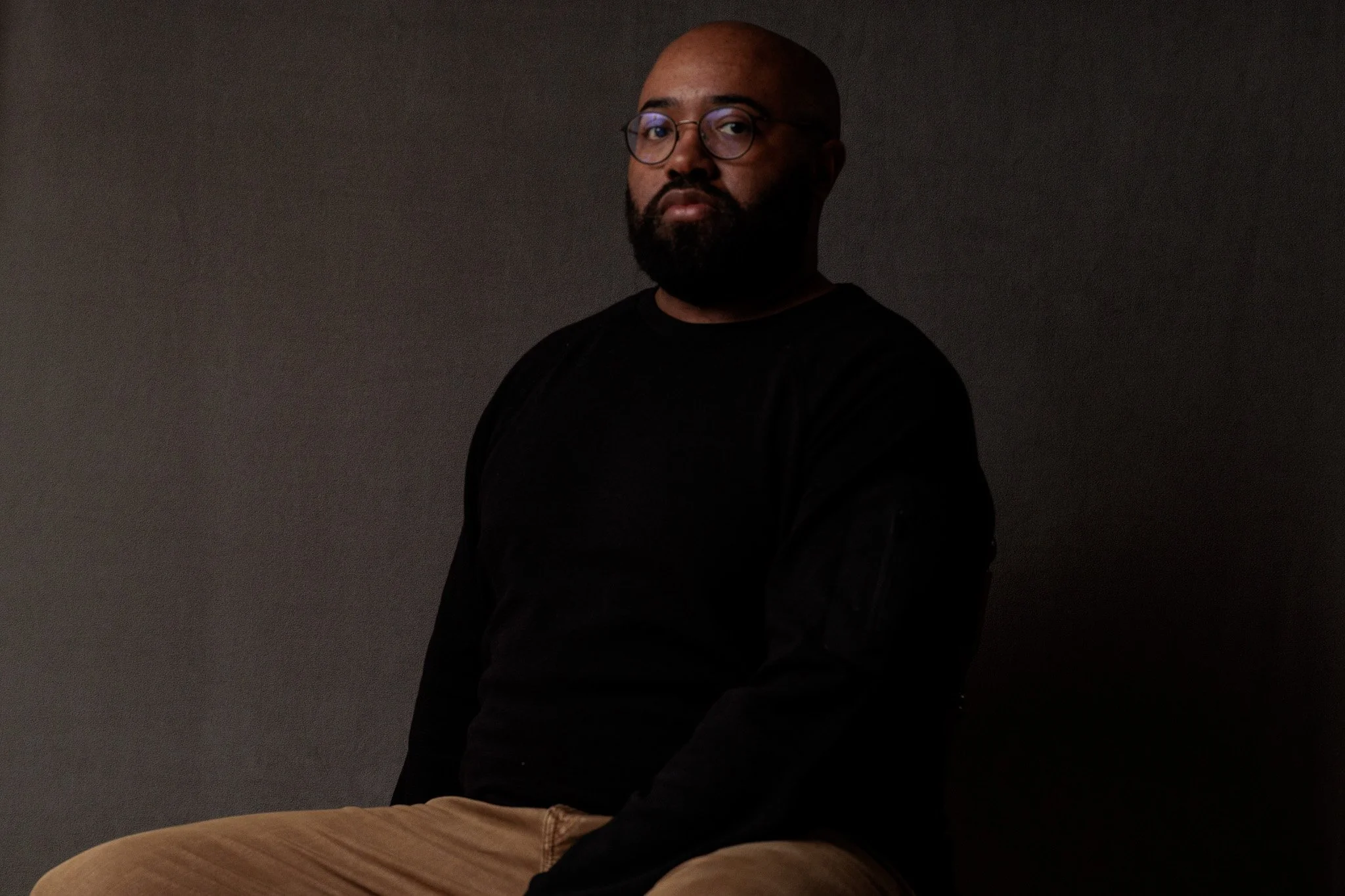 Antonio Davis, documentary and editorial photographer, in a low-key self-portrait against a dark backdrop.