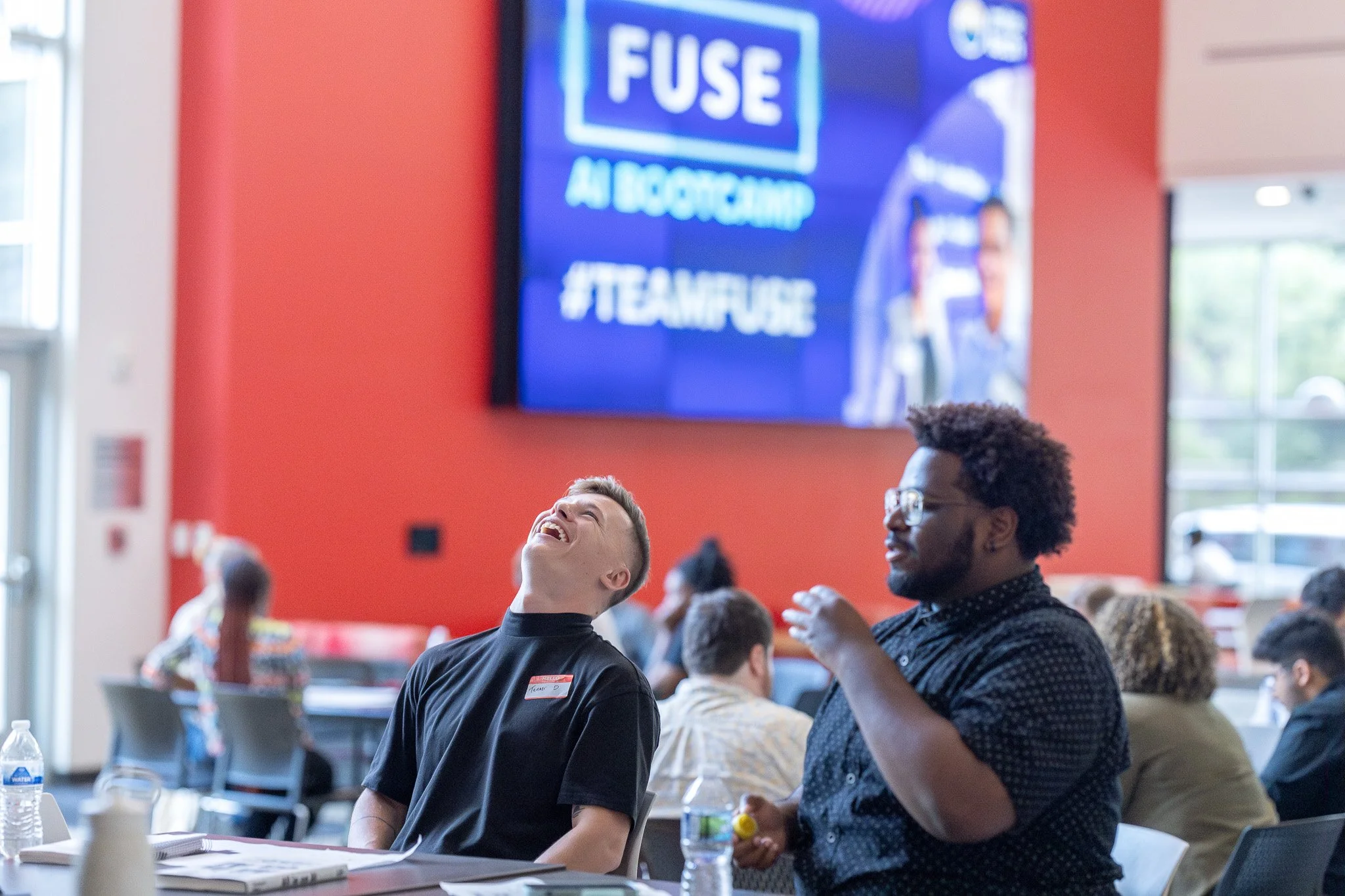 Two young men share a laugh at a college tech and AI bootcamp in Milwaukee.
