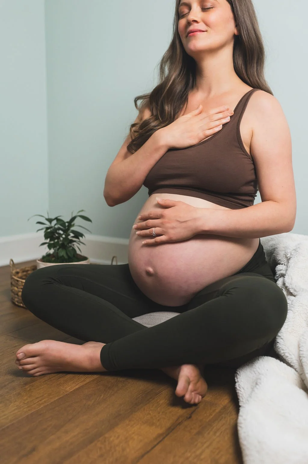 pregnant woman smiles and holds her hands on her heart and her belly as she envisions her empowered birth