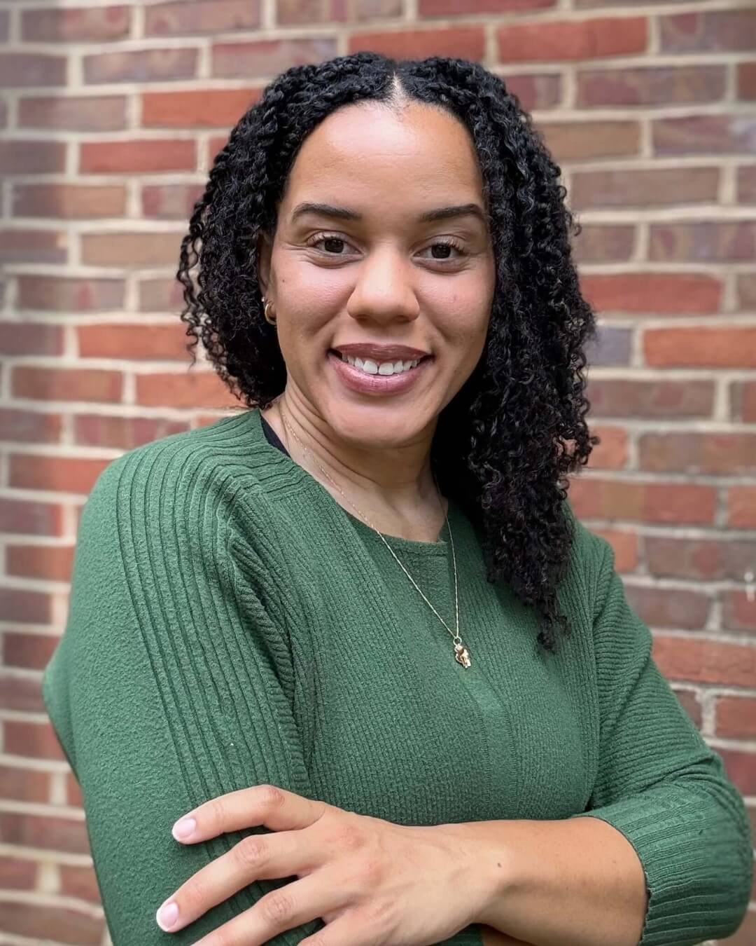 Dyane Loney pelvic floor physical therapist smiles while wearing a green shirt in front of a brick wall
