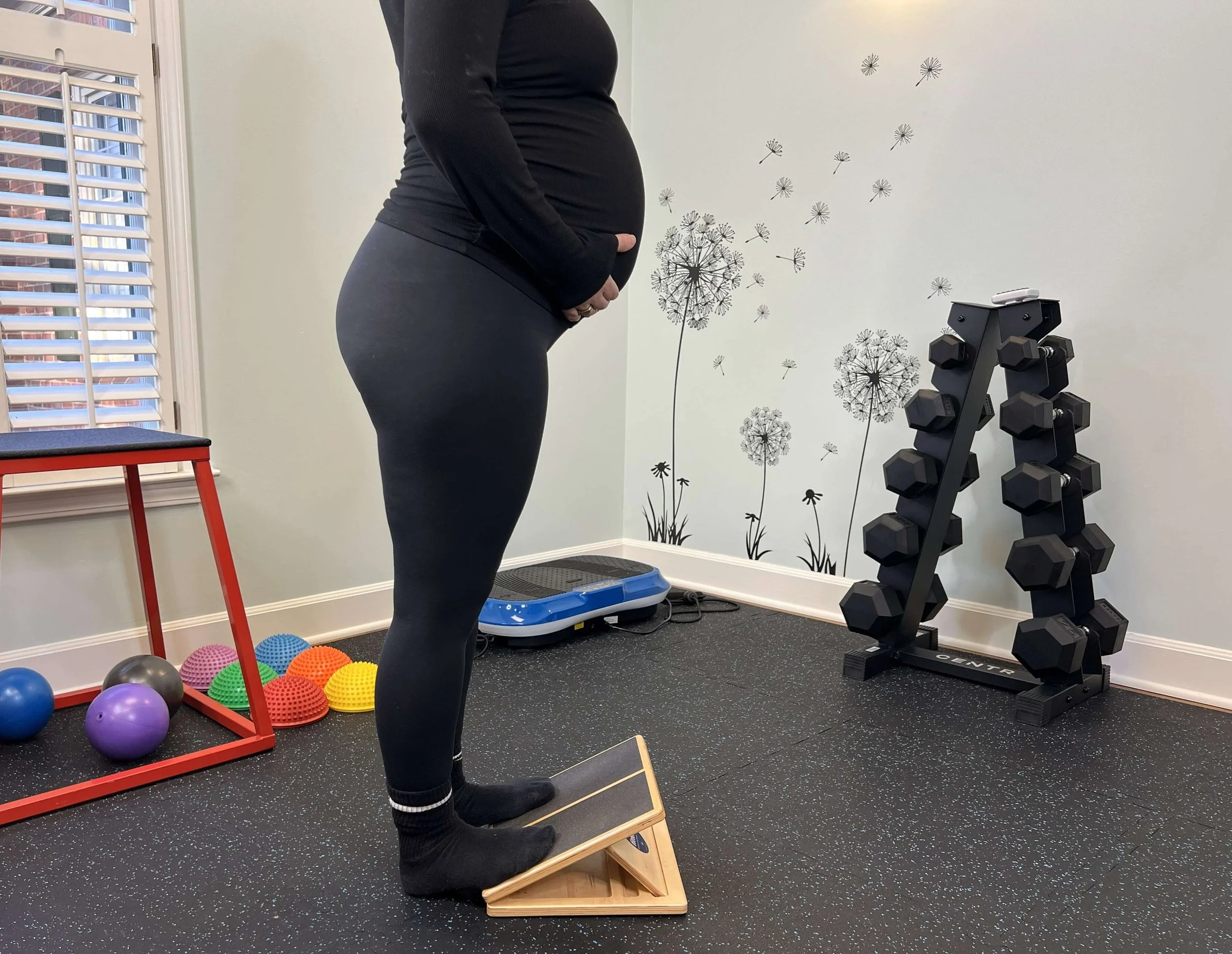 Pregnant mom using calf stretch board in the gym at Renew Pelvic Health