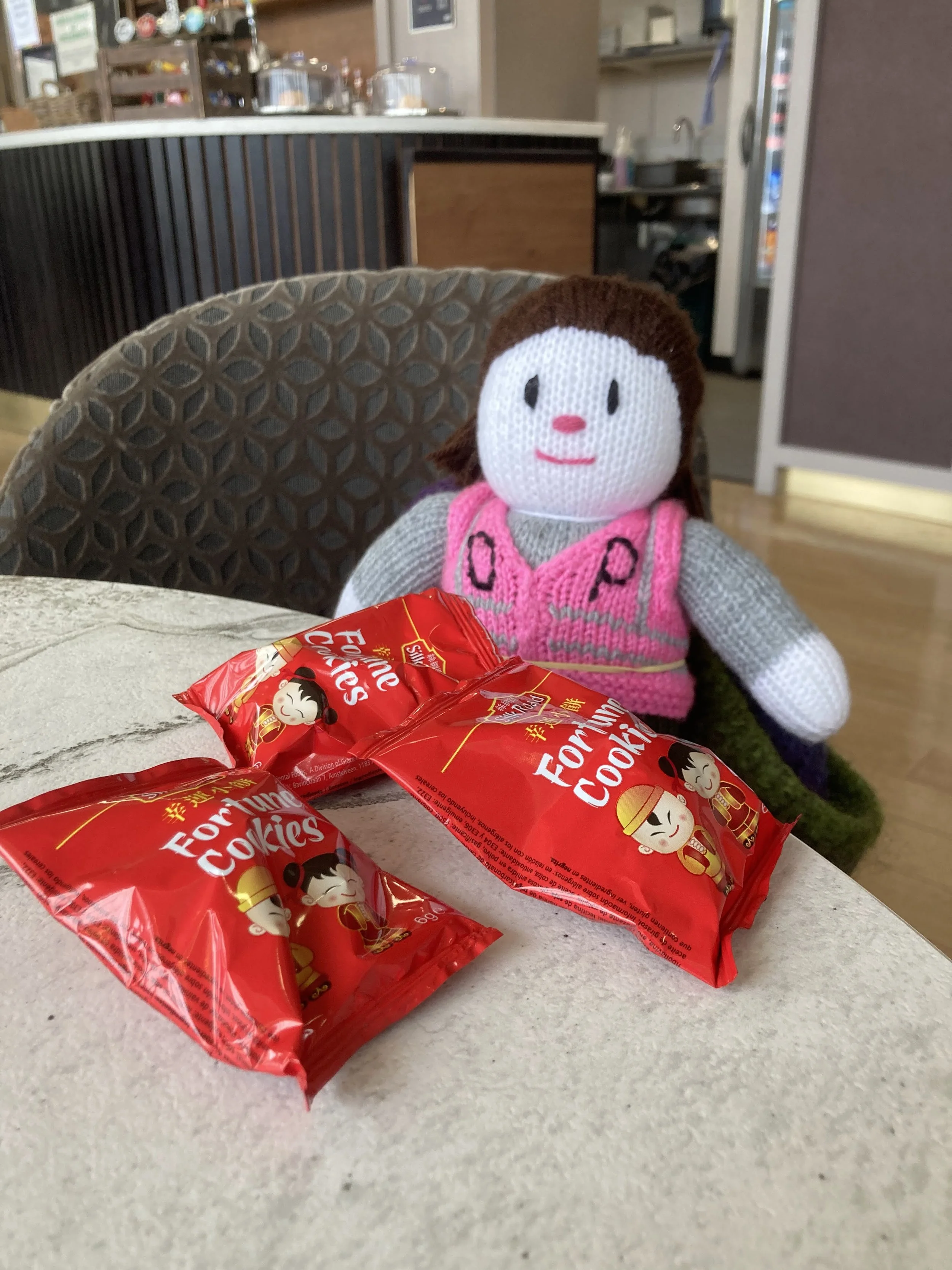 A knitted Poily Pointer enjoying some fortune cookies