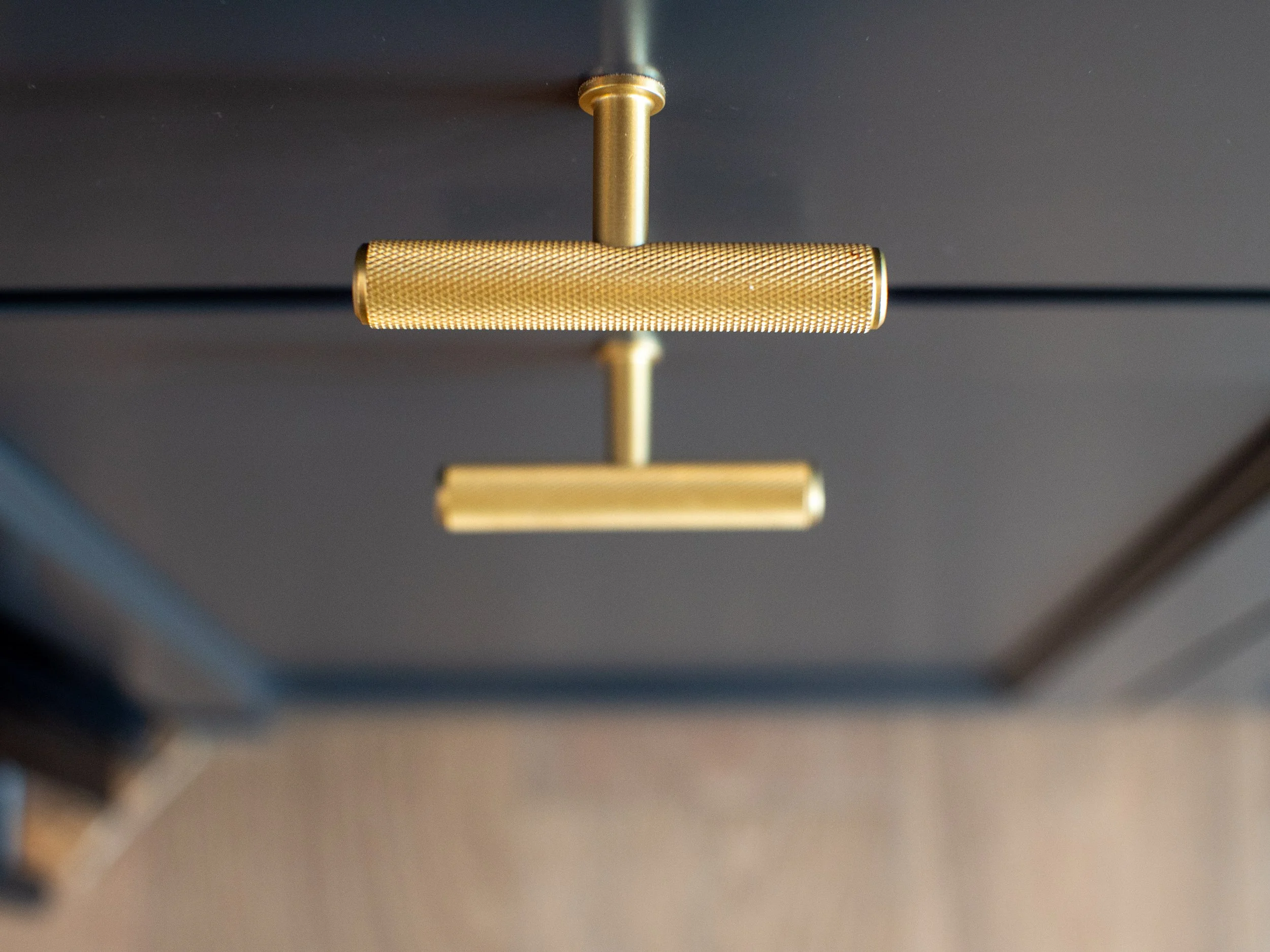 Close-up of a modern, gold-colored, adjustable ceiling light fixture with a textured cylindrical shade and a sleek, minimalistic design.