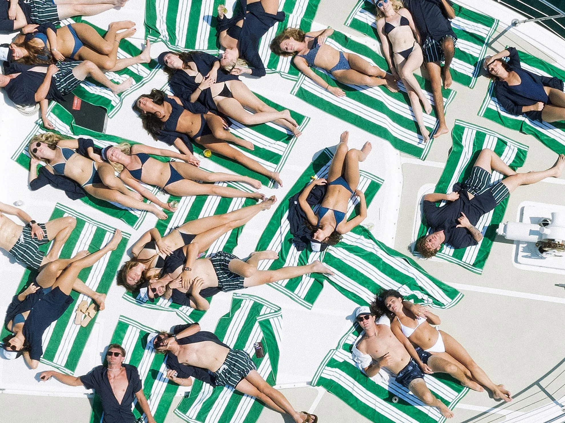 Bridal party celebrating aboard a yacht in Laguna Beach before the wedding weekend, featuring striped beach towels, coastal luxury styling, and a fun bachelor and bachelorette party atmosphere.