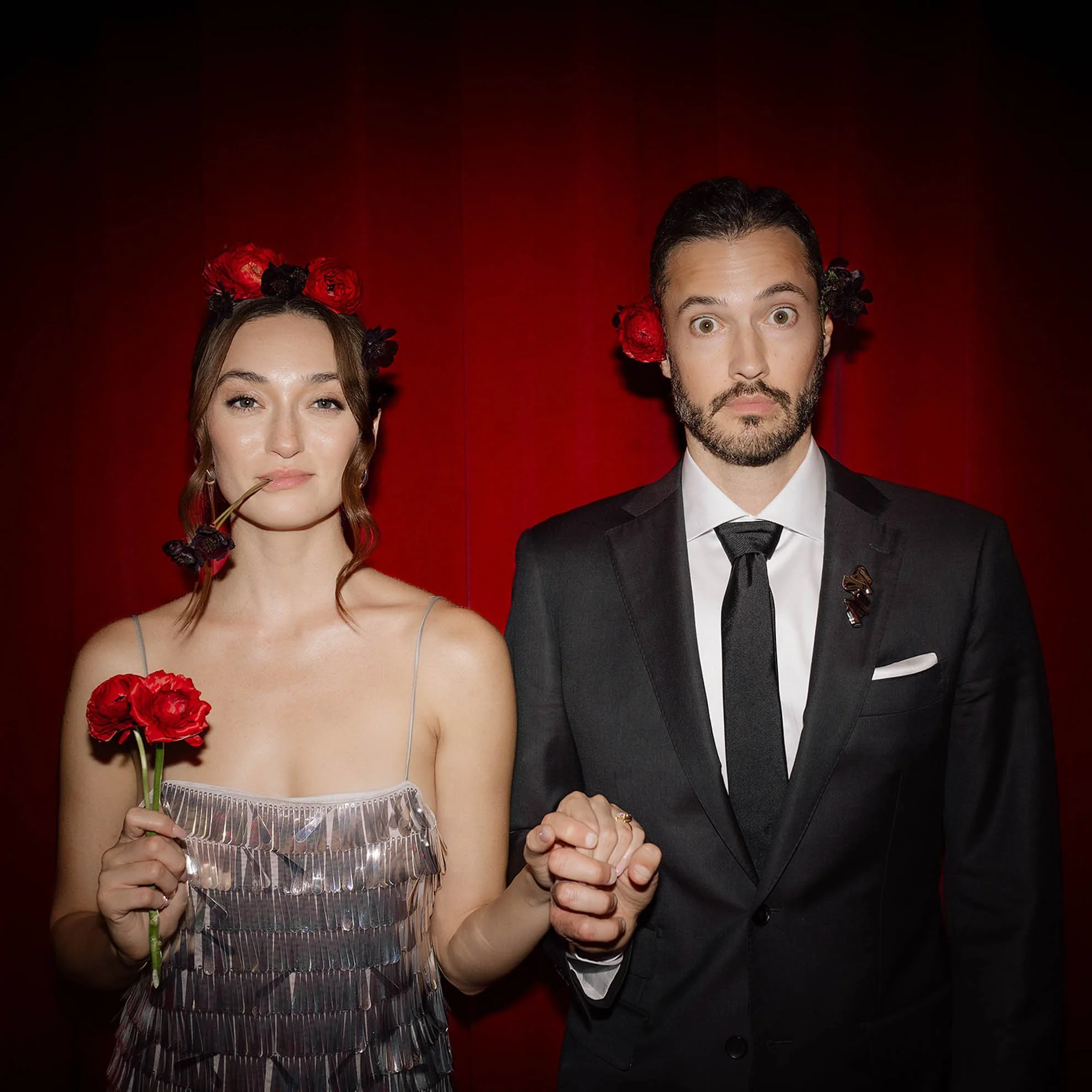 Newlywed couple in second look holding florals and playfully posing for the camera, capturing a fun and candid wedding moment