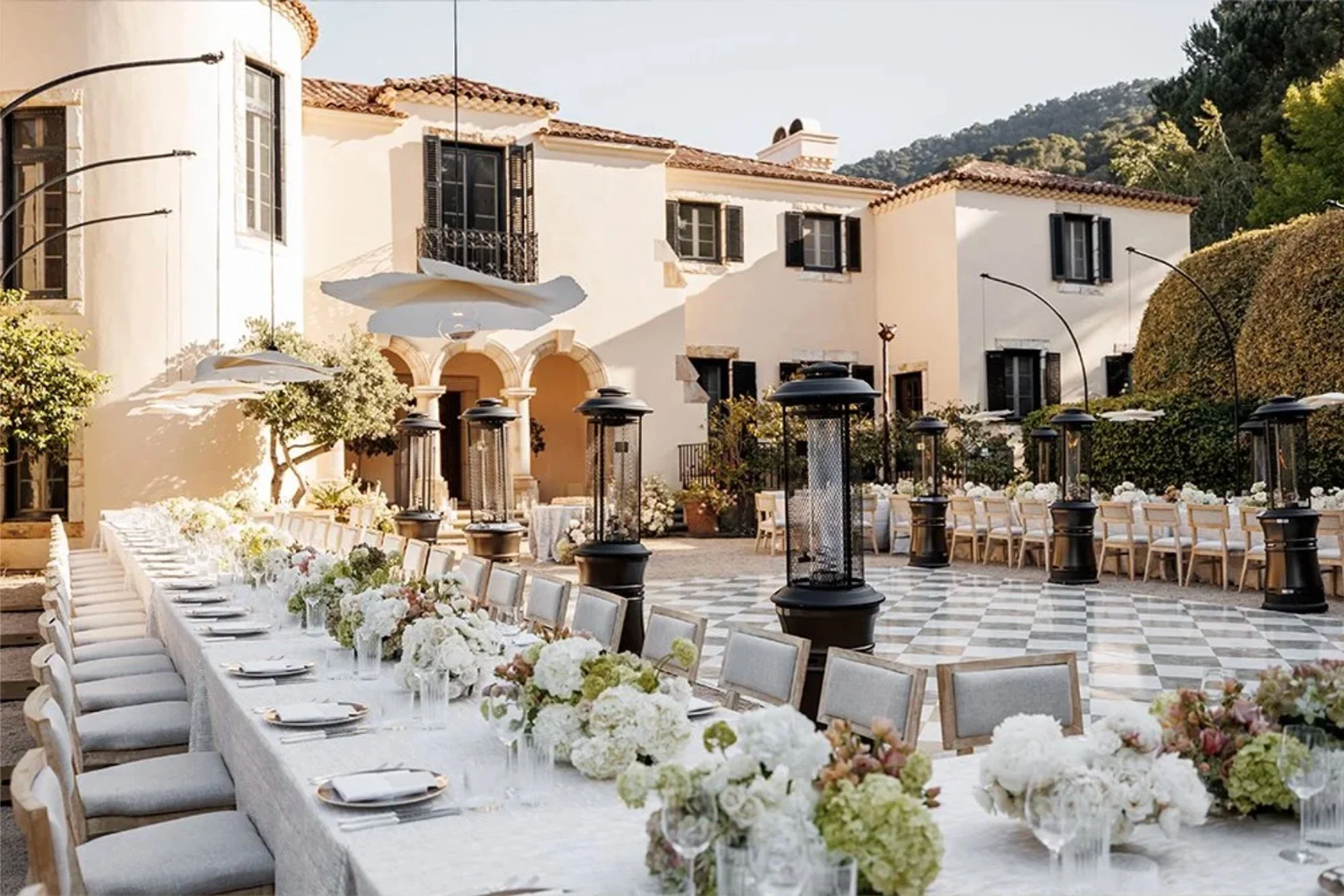 Outdoor estate wedding reception dinner featuring modern tablescapes, elegant floral centerpieces, and guest tables thoughtfully arranged to frame the central dance floor, designed and produced by a luxury full-service wedding planning team.