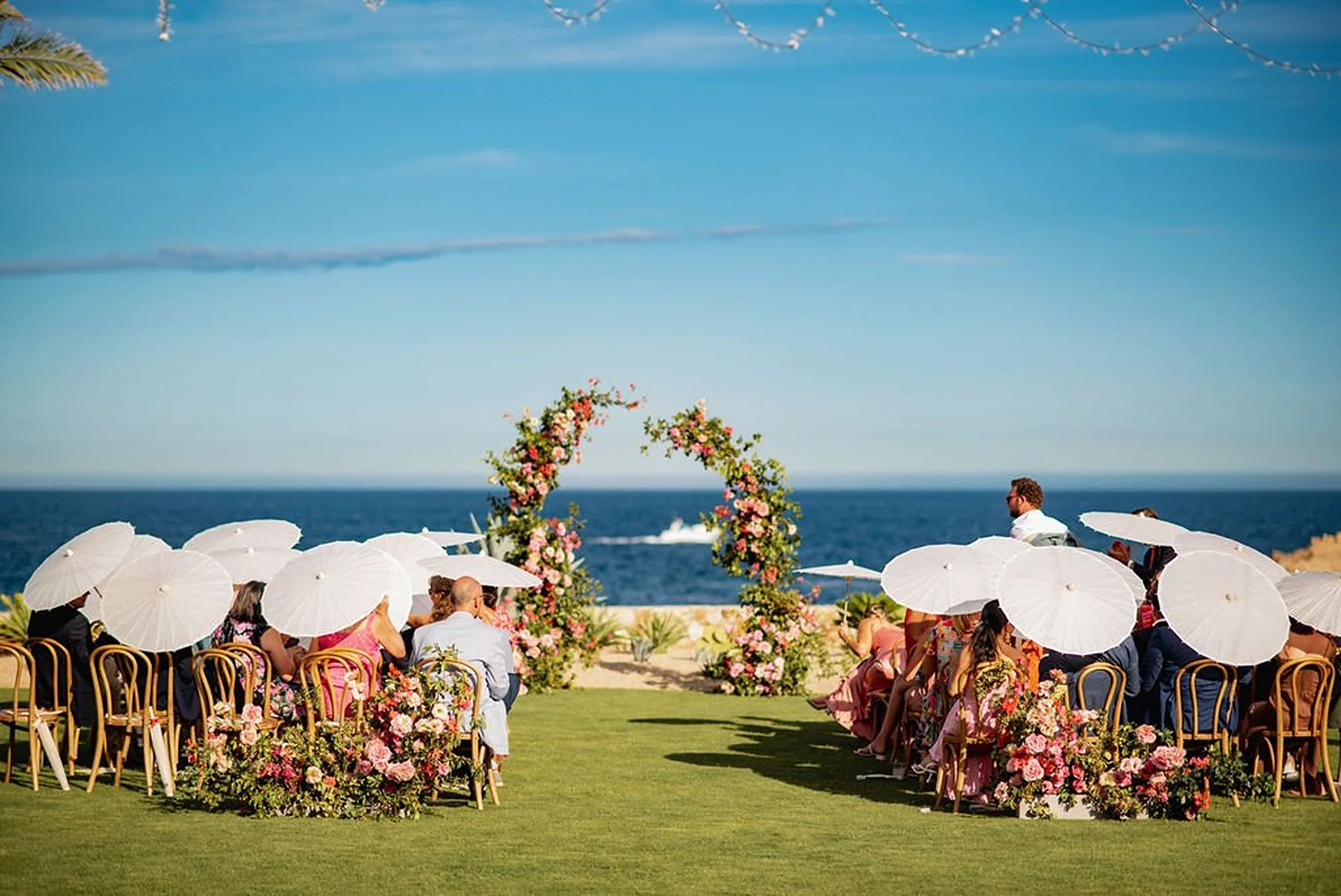 Montage Los Cabos Mexico destination wedding ceremony with floral arch, ocean views, and guests on a lush lawn