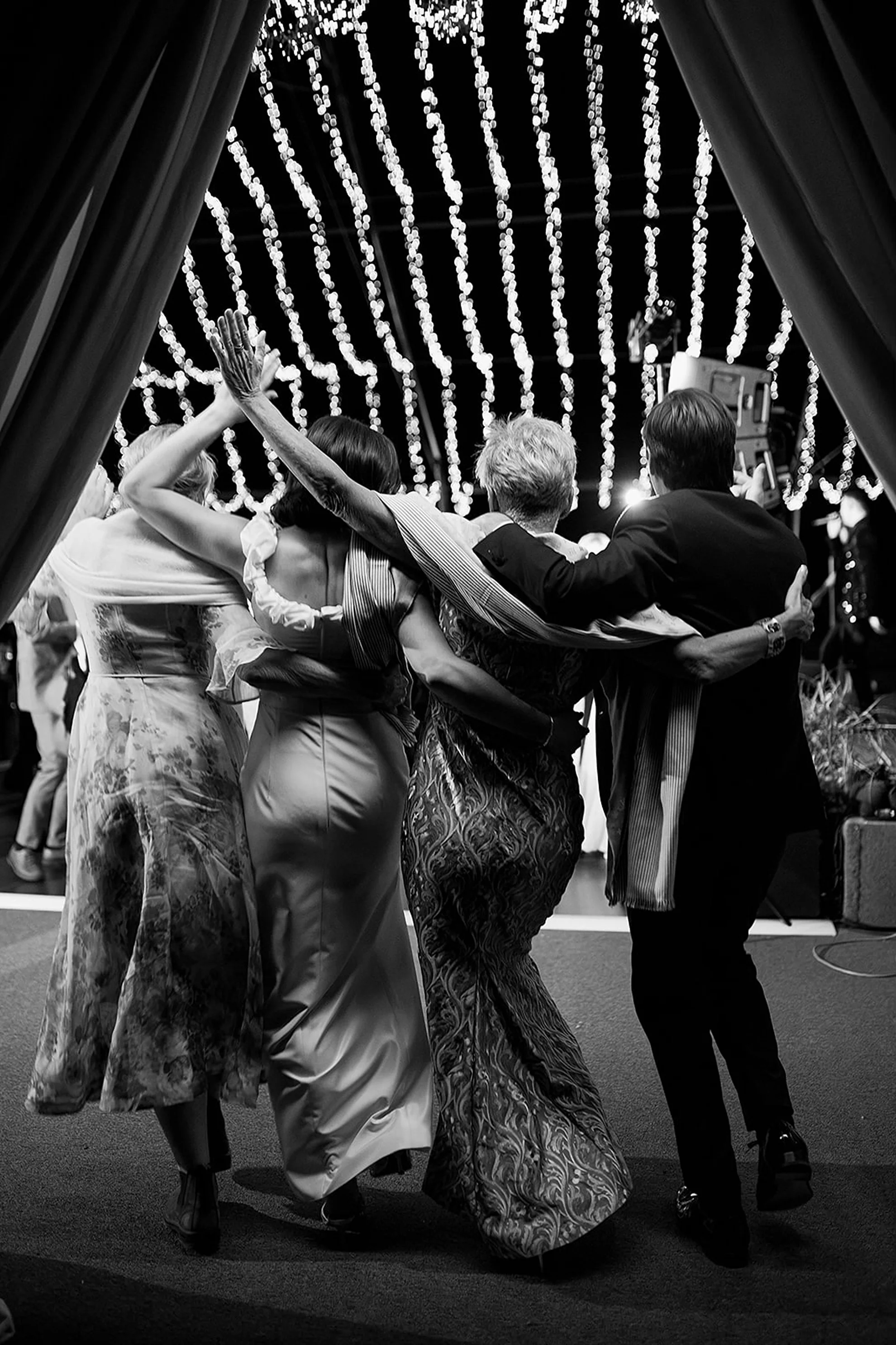 Newlyweds dancing into an open-air tented reception during a high-energy luxury wedding reception with guests celebrating beneath elegant lighting and modern event design.