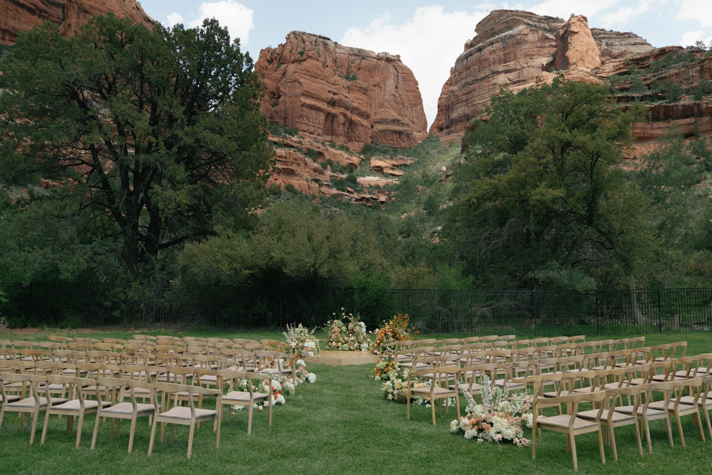 Outdoor wedding ceremony at Enchantment Resort in Sedona, Arizona featuring modern floral design set amongst red rock canyon views and a dramatic desert landscape.