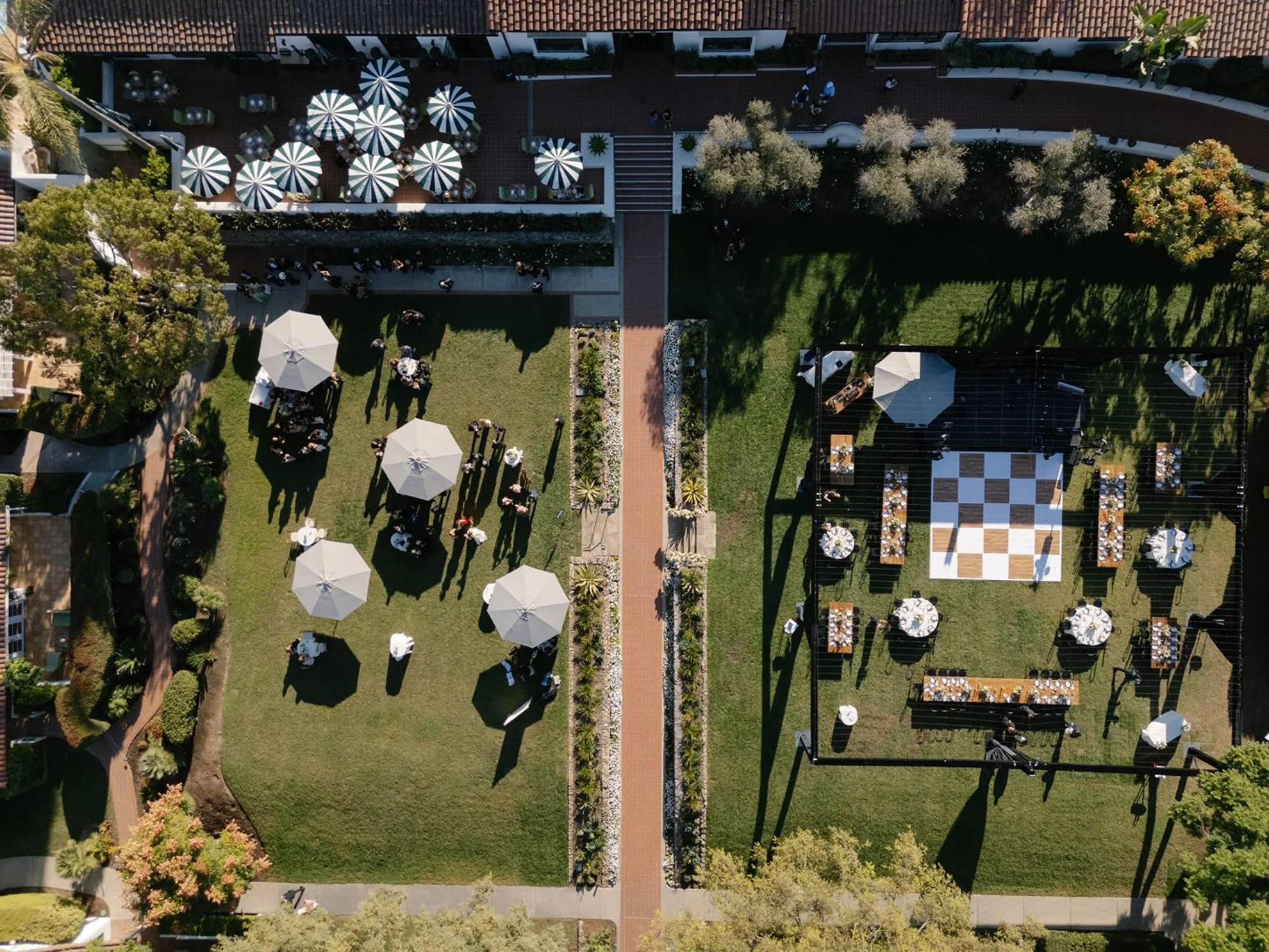 Estate-inspired garden wedding reception featuring parasols, elevated cocktail-style dining, and abundant lush greenery, thoughtfully designed and produced by a luxury full-service wedding planning team.
