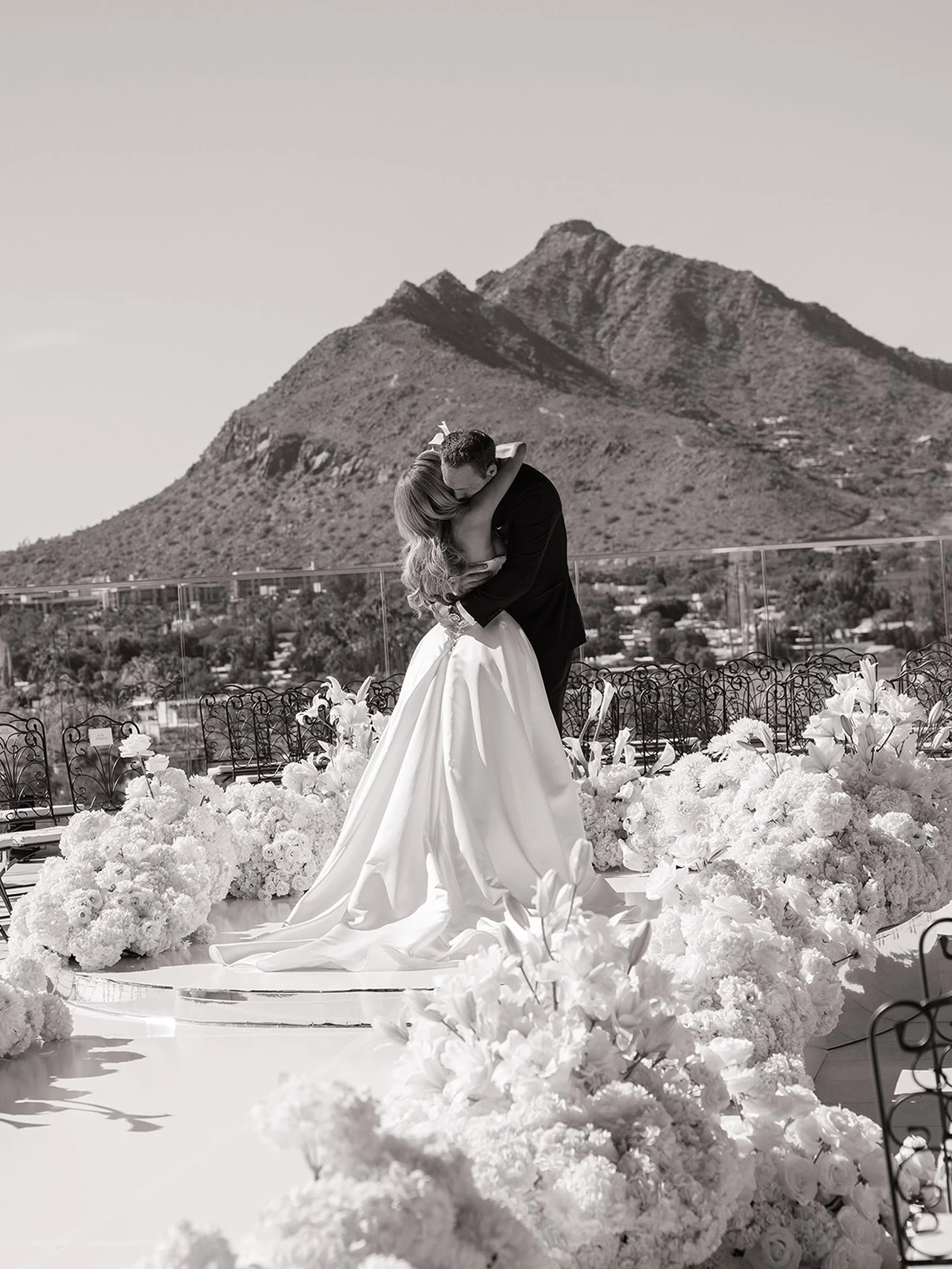 Luxury wedding ceremony in Scottsdale, Arizona with mountain views and the couple surrounded by white floral arrangements