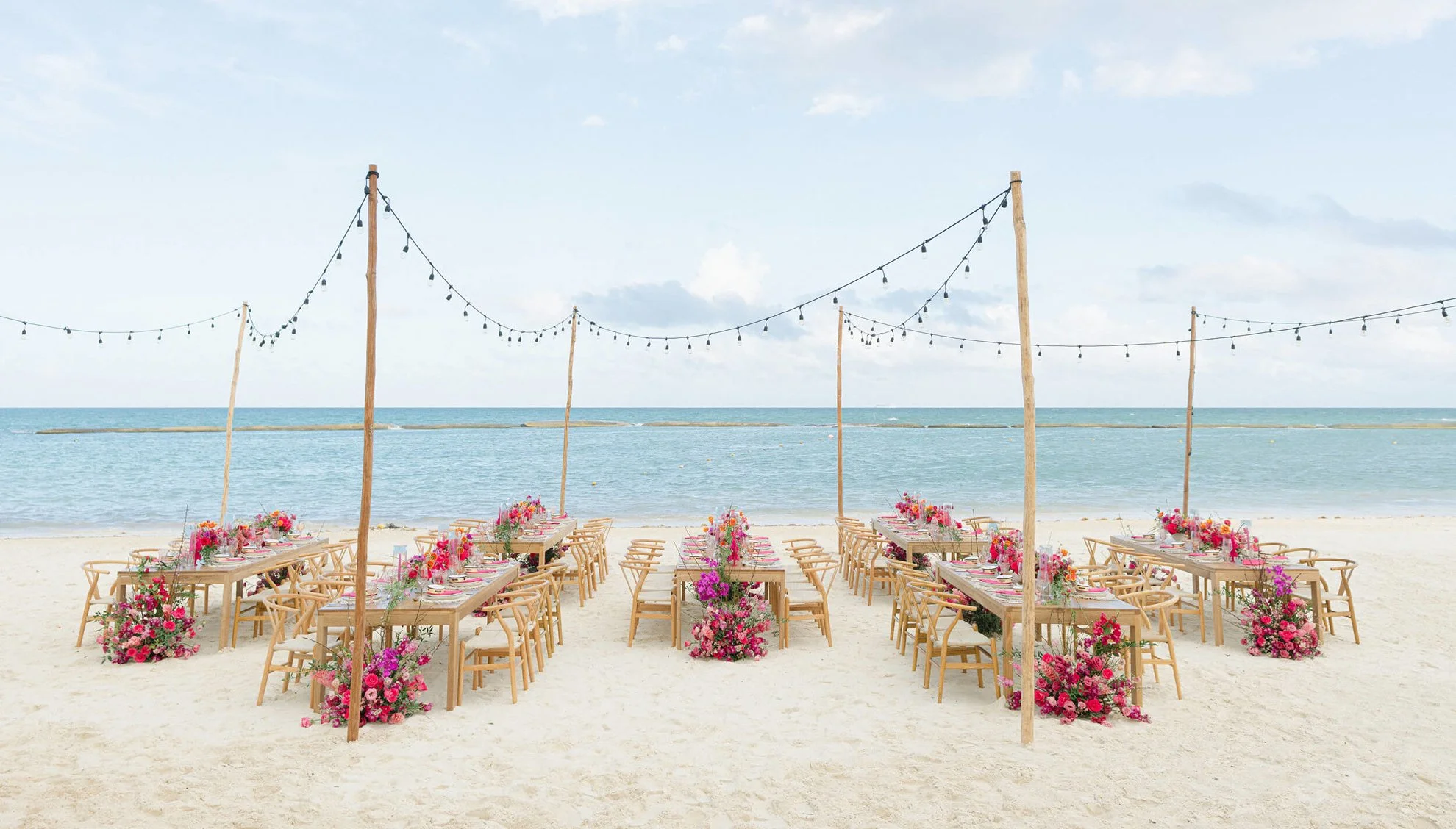 Montage Los Cabos beach reception with wood tables, string lights, pink florals, and ocean views at a luxury wedding venue in Mexico