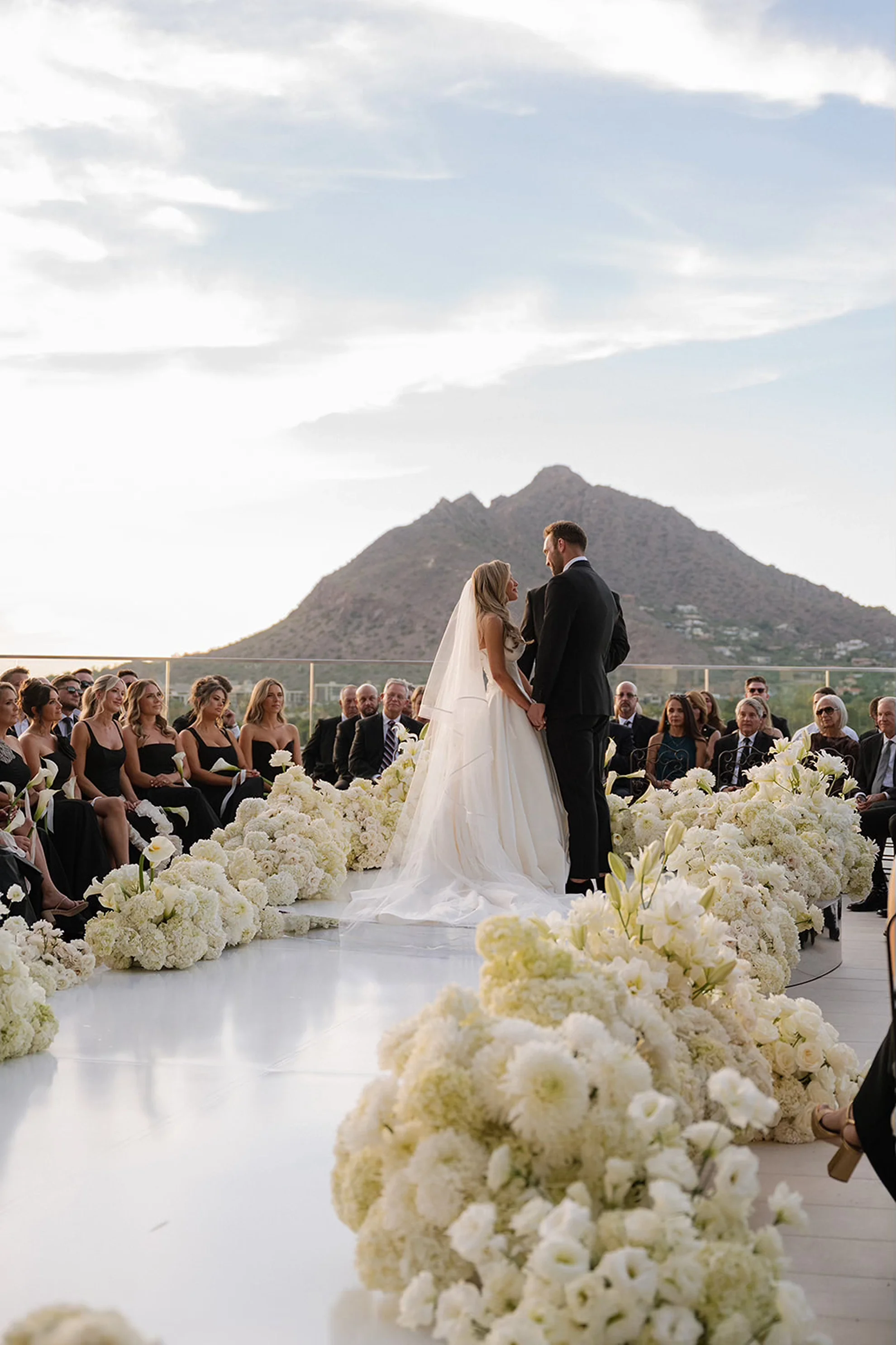 Luxury outdoor wedding ceremony with all-white decor on the rooftop of Caesars Republic Scottsdale, overlooking the surrounding mountains.