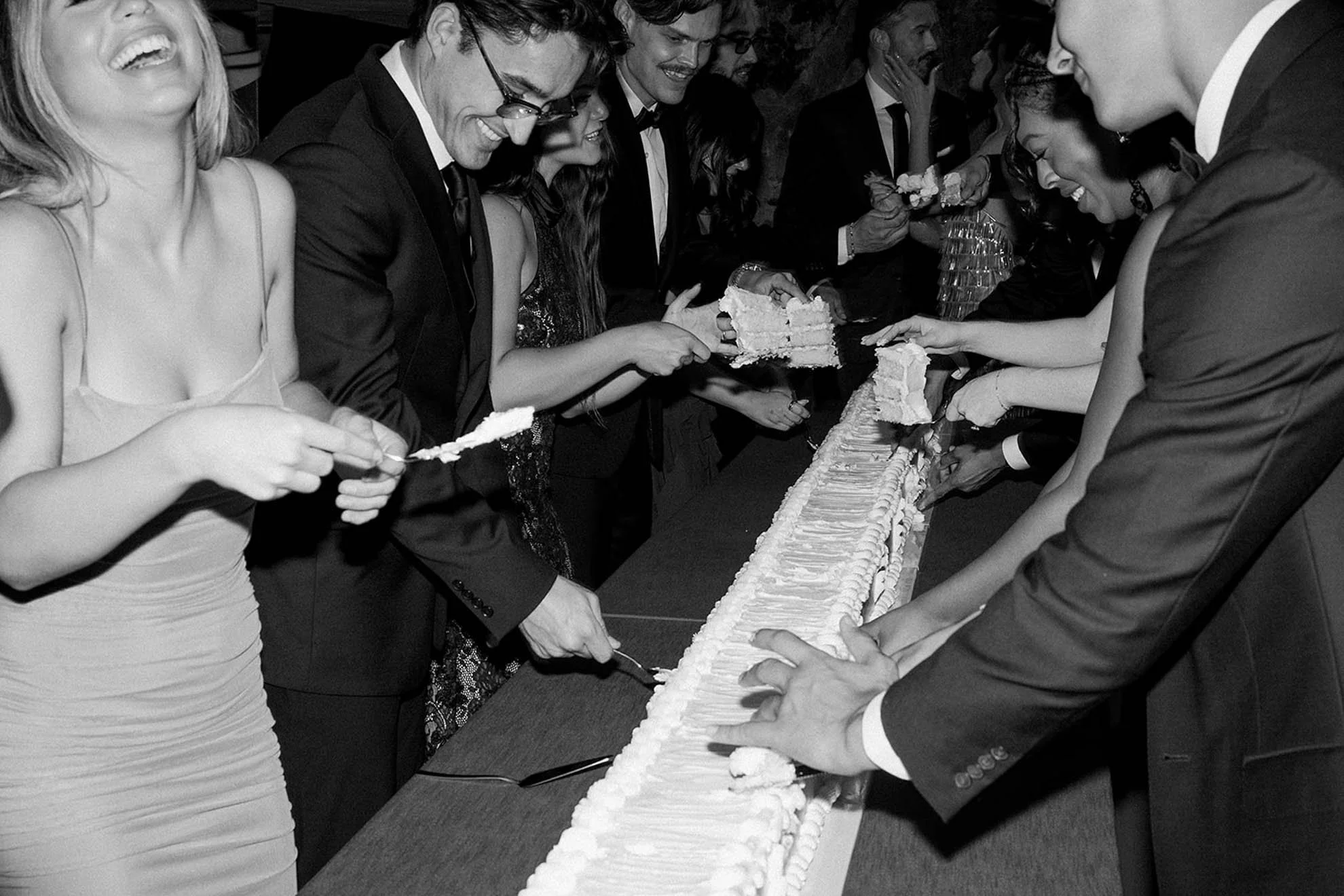 Guests gathered around a 16-foot wedding cake during cake cutting, creating an interactive and memorable celebration moment centered on shared experience