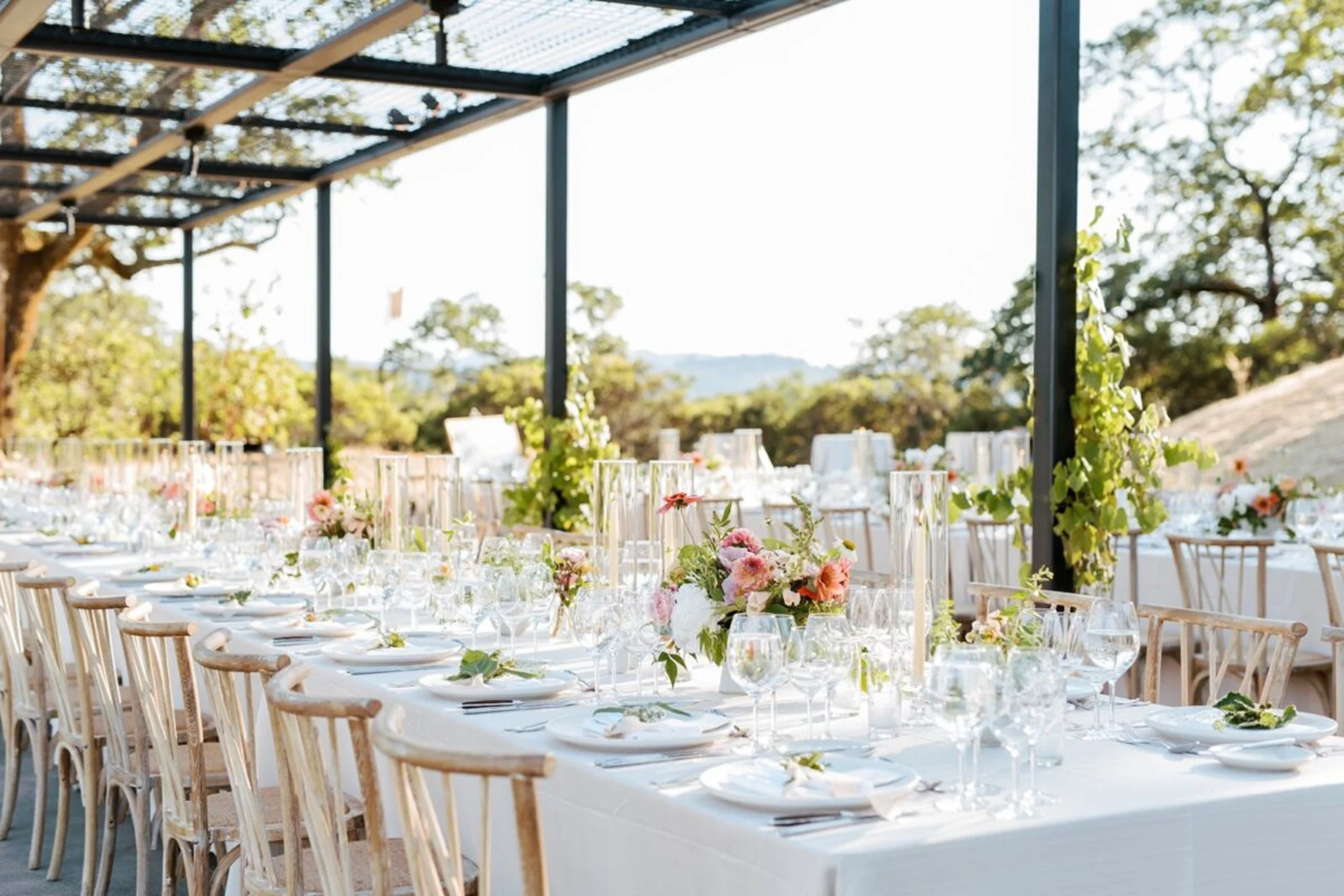 Luxury modern outdoor wedding reception featuring clean-lined tablescapes, minimalist floral centerpieces, and wooden dining chairs, thoughtfully designed by a full-service wedding planning and production team.