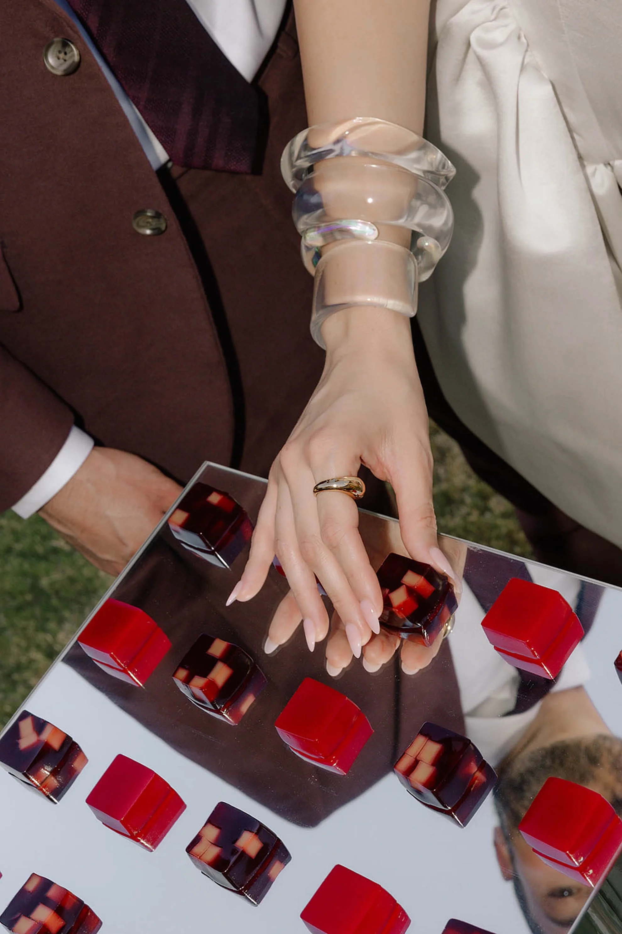 Modern jelly square hors d’oeuvres displayed on a mirrored platter during a luxury wedding welcome party with elevated catering presentation and contemporary event styling.