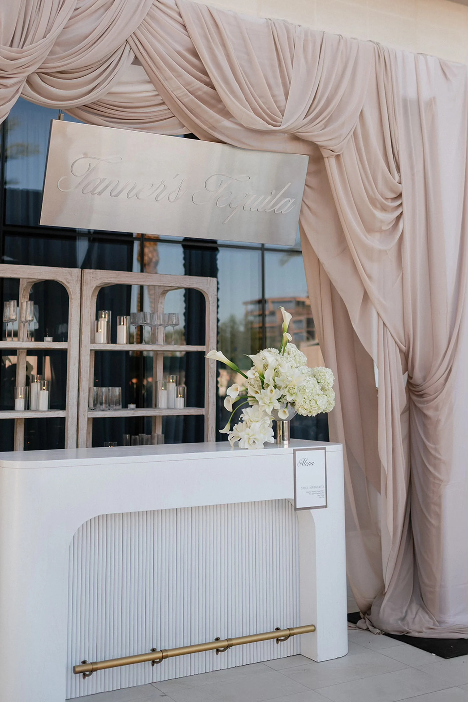 Outdoor wedding bar with soft white draping and neutral tones, designed as part of a luxury wedding celebration