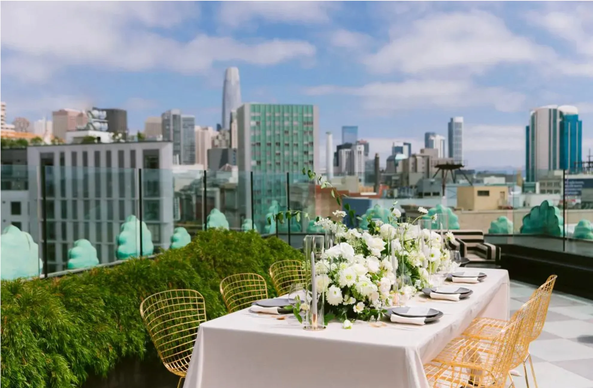 Luxury rooftop wedding reception dinner featuring sweeping city skyline views, neutral white floral arrangements, and modern tablescapes, expertly designed and produced by a full-service wedding planning team.