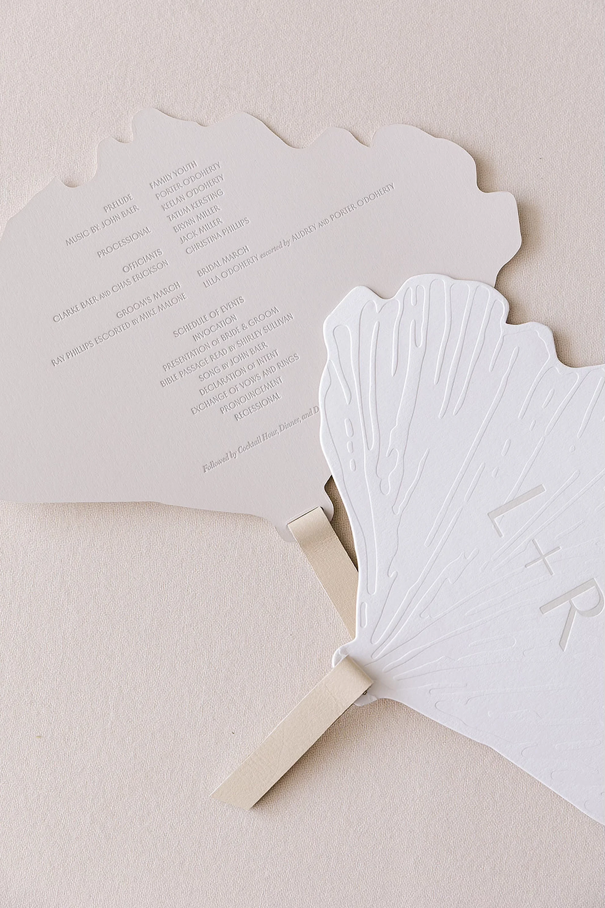 Luxury wedding ceremony program designed as a handheld fan featuring custom letterpress printing and elegant stationery details.