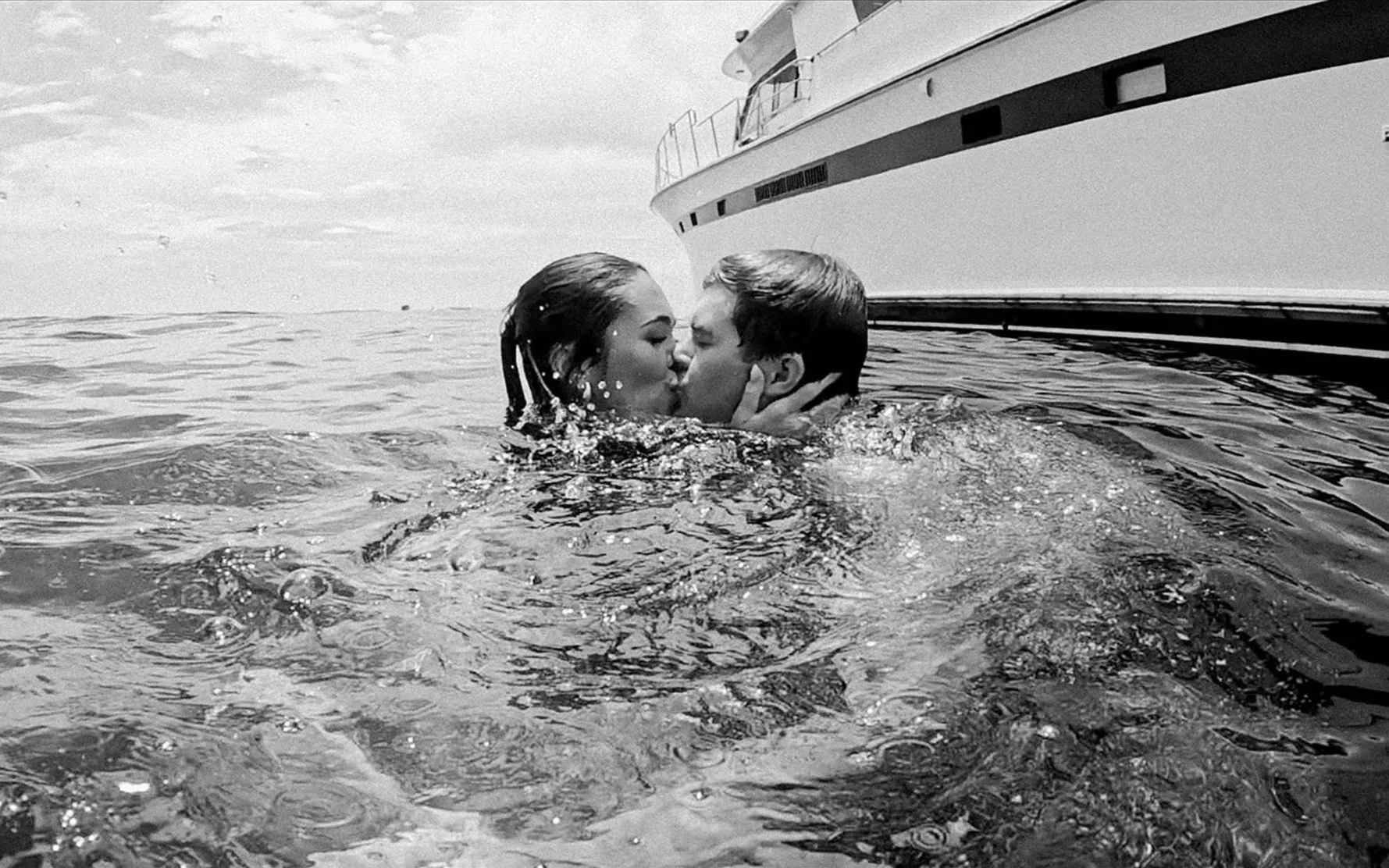 Couple kissing in the ocean during a Laguna Beach yacht party, capturing a candid, cinematic moment from a multi-day destination wedding celebration