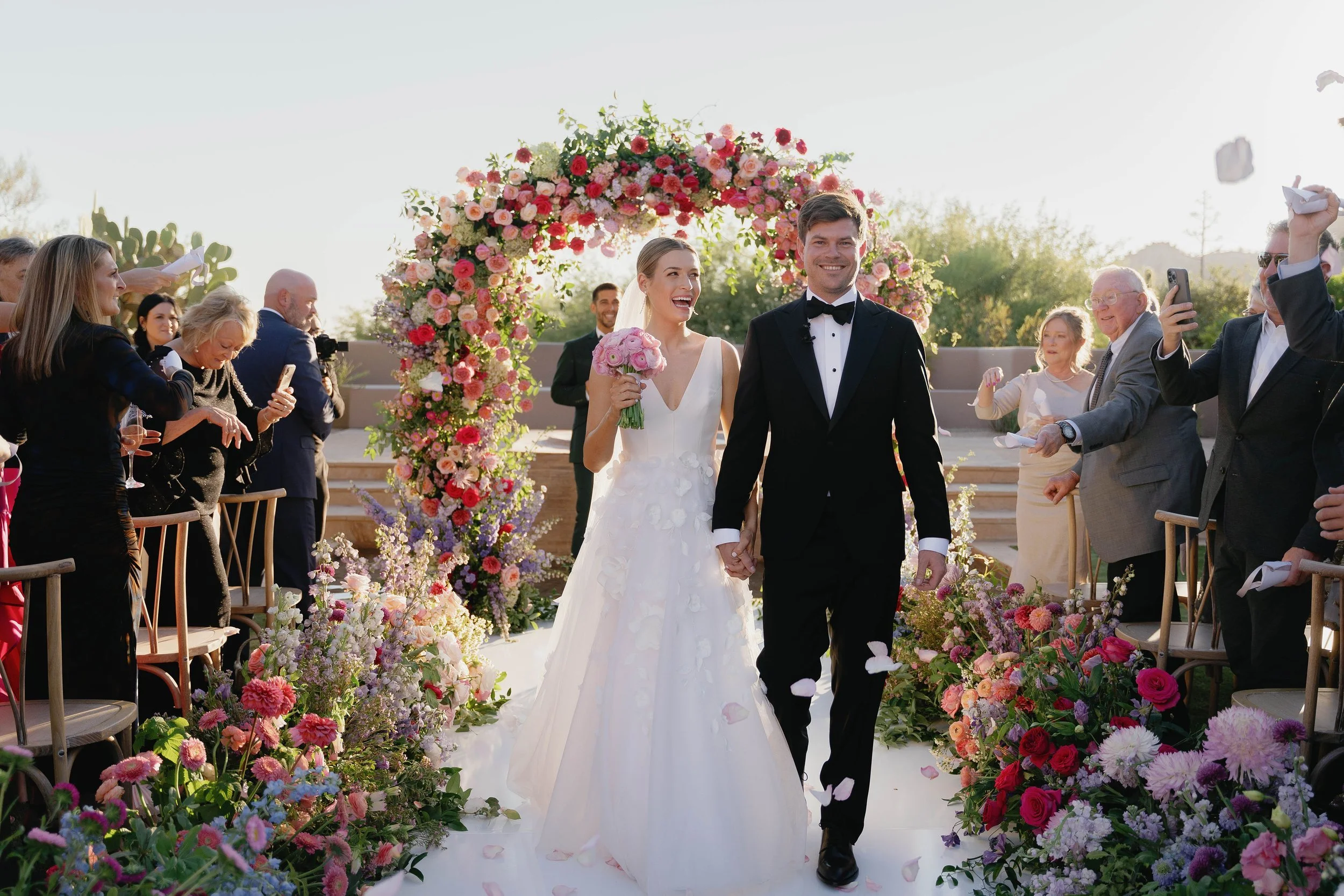 Bold, colorful florals line the aisle as wedding couple walks down after ceremony at Four Seasons Scottsdale