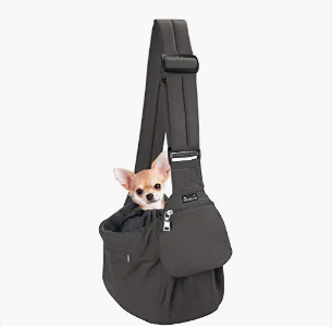 A black pet carrier sling with a small Chihuahua peeking out of the opening.