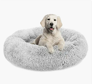 A cute puppy sitting in a fluffy, round gray pet bed