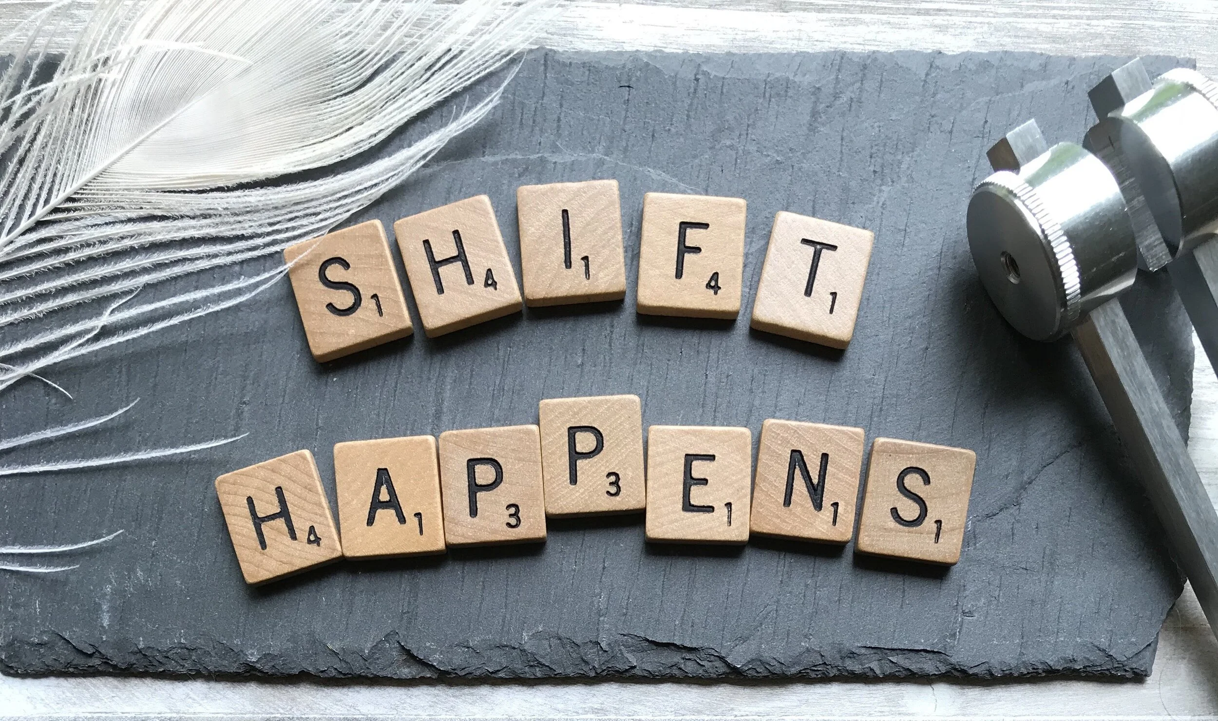 Scrabble tiles spell out "Shift happens"
