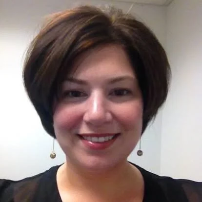 Annette Garsteck smiling in an office during an earlier chapter of her career.