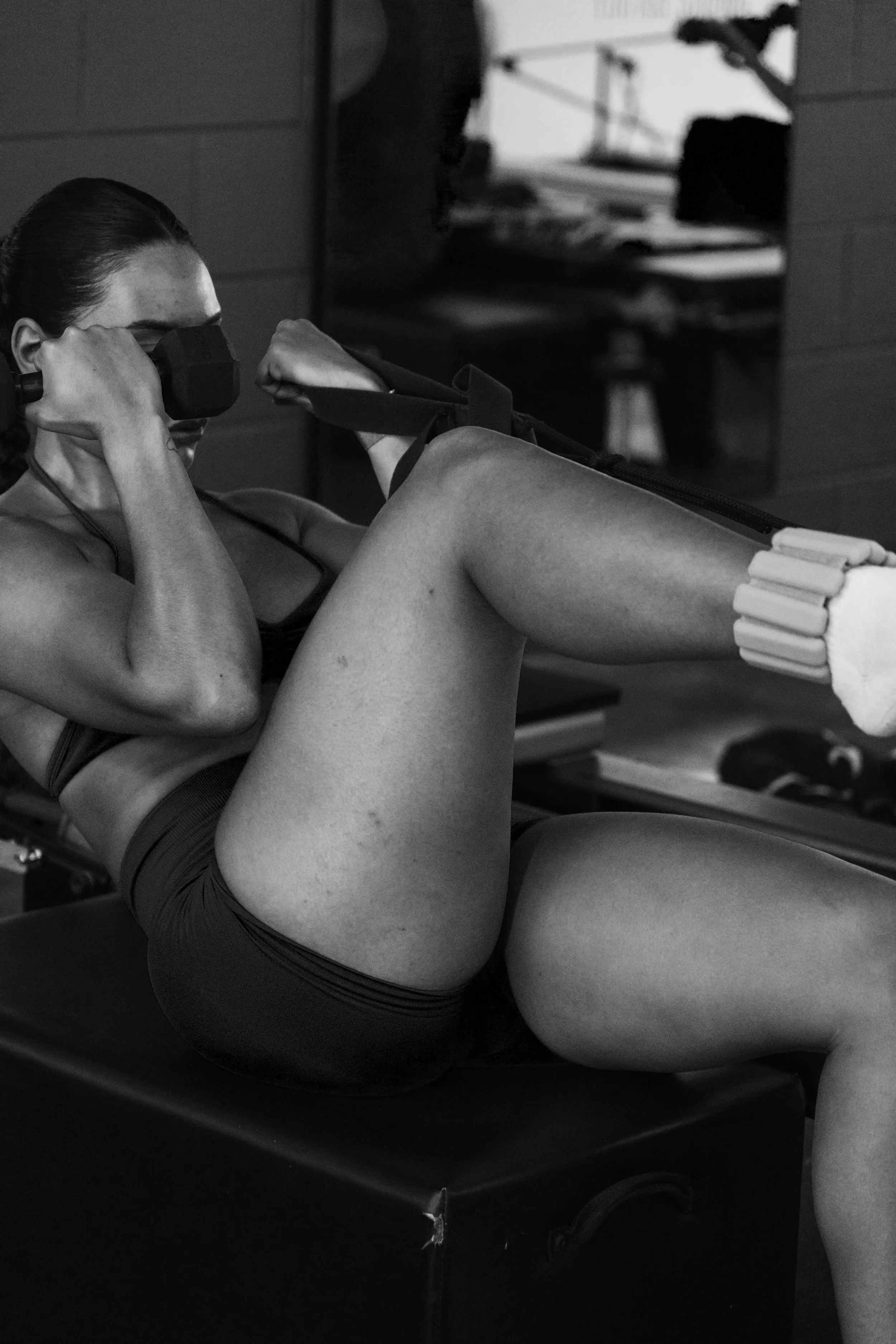 A woman in orange workout gear using a resistance band during exercise at a gym.