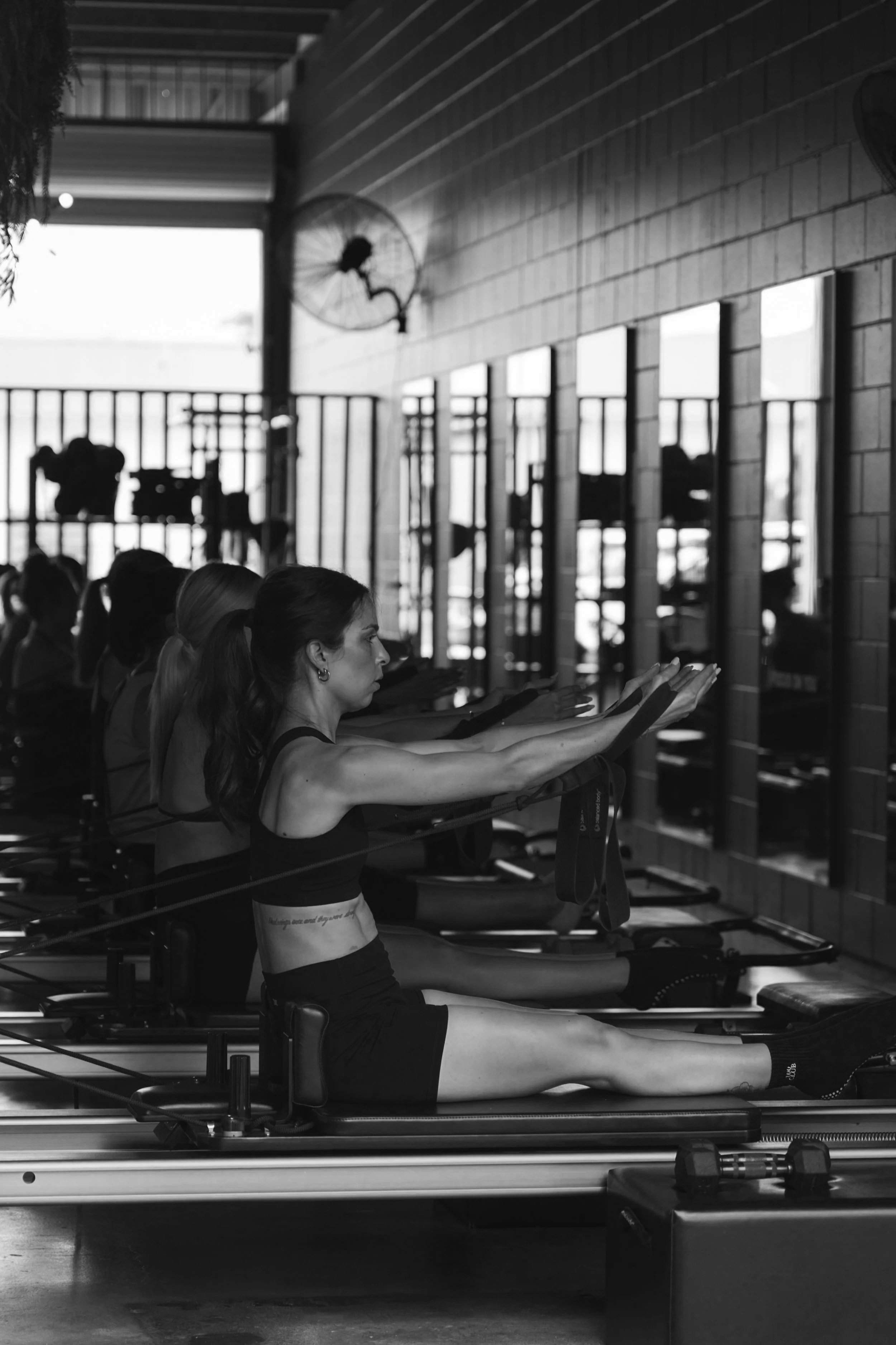 Women practicing Pilates on reformer machines in a fitness studio.