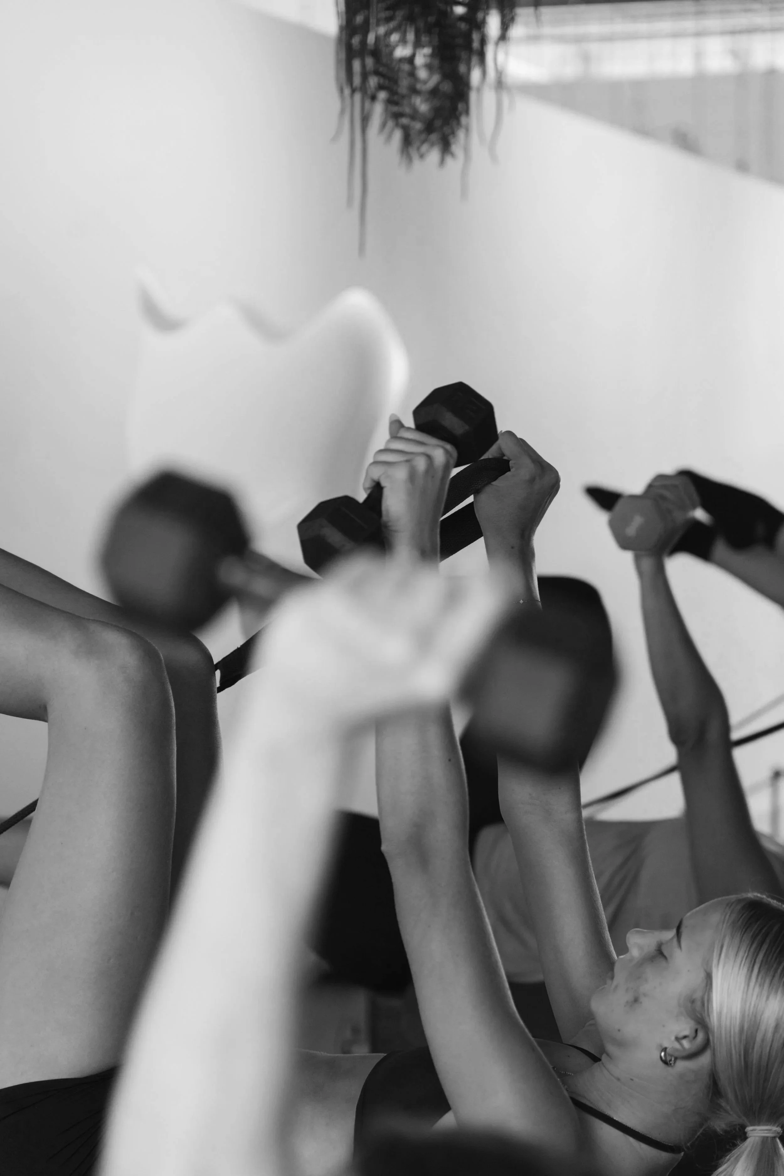 People lifting dumbbells during a workout session at a gym or fitness class.