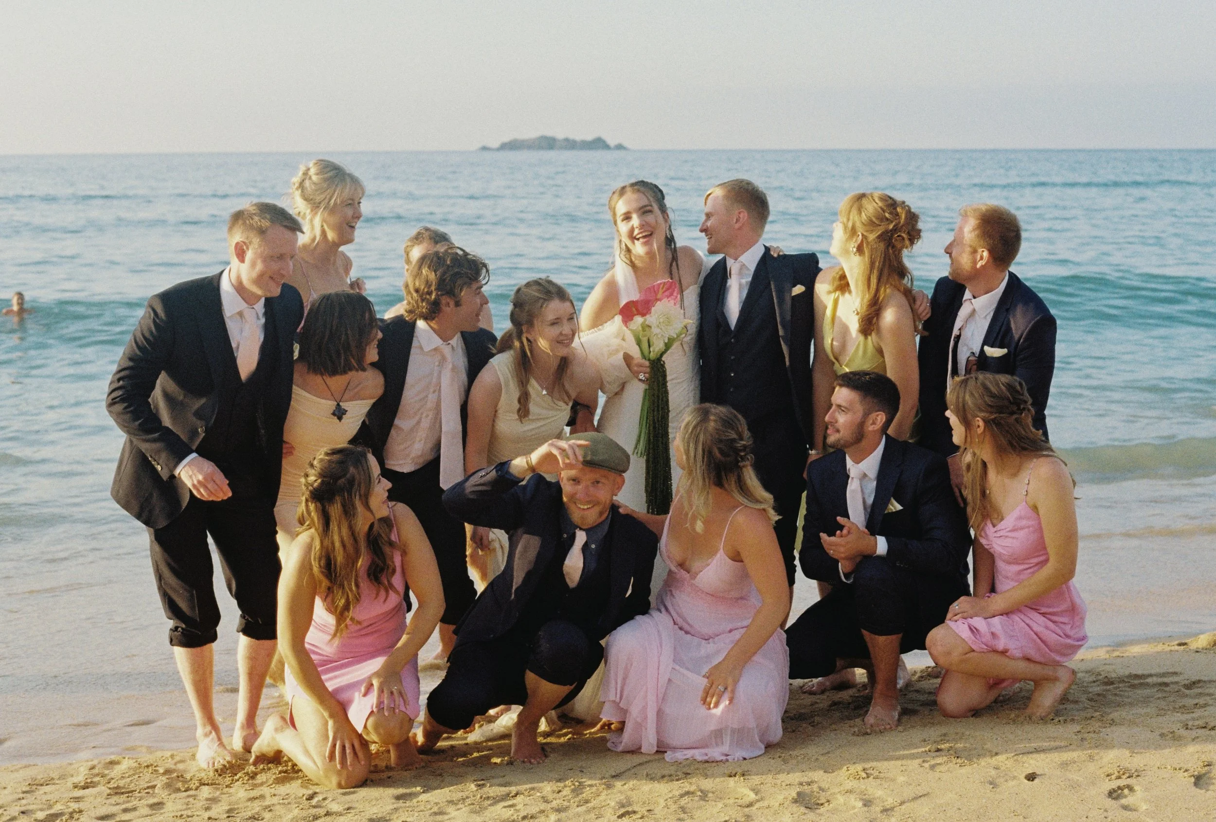 big chaotic group photo shot on film by the sea of the bridal party