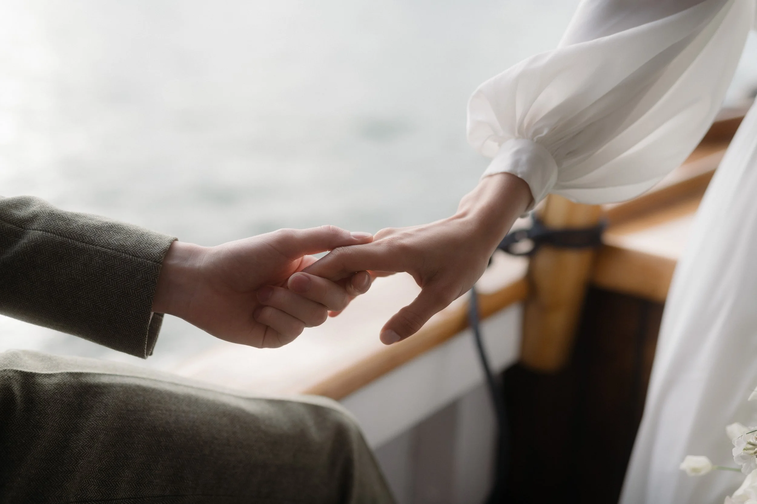 poet sleeves on a wedding gown with the sea in the background and tender moments during an elopement on a boat and cruise up the river in cornwall