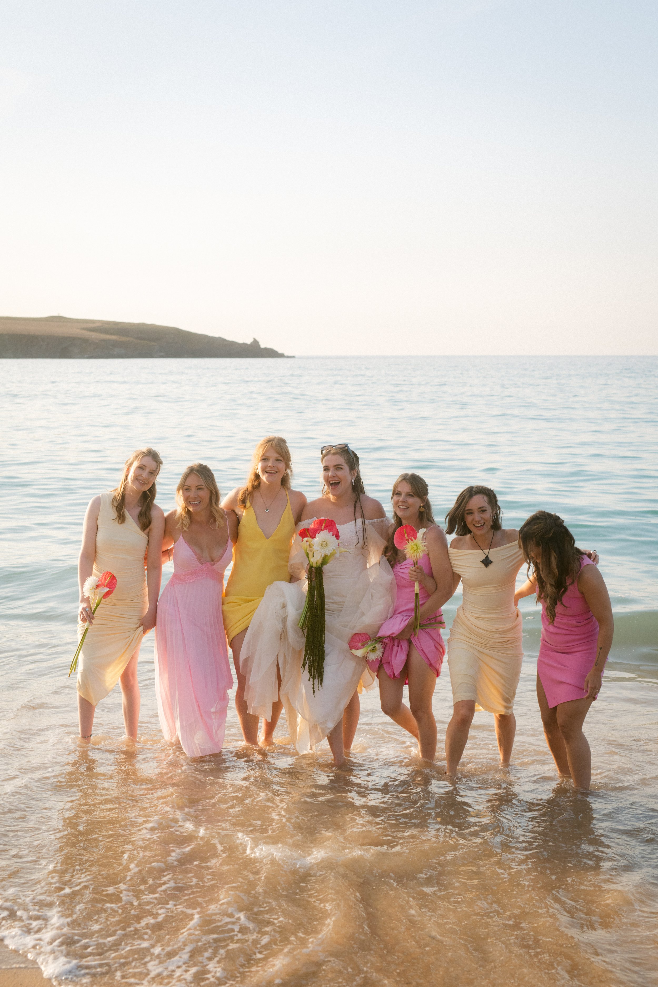 colourful bridesmaids in the sea for candid group portraits at a cornwall beach wedding