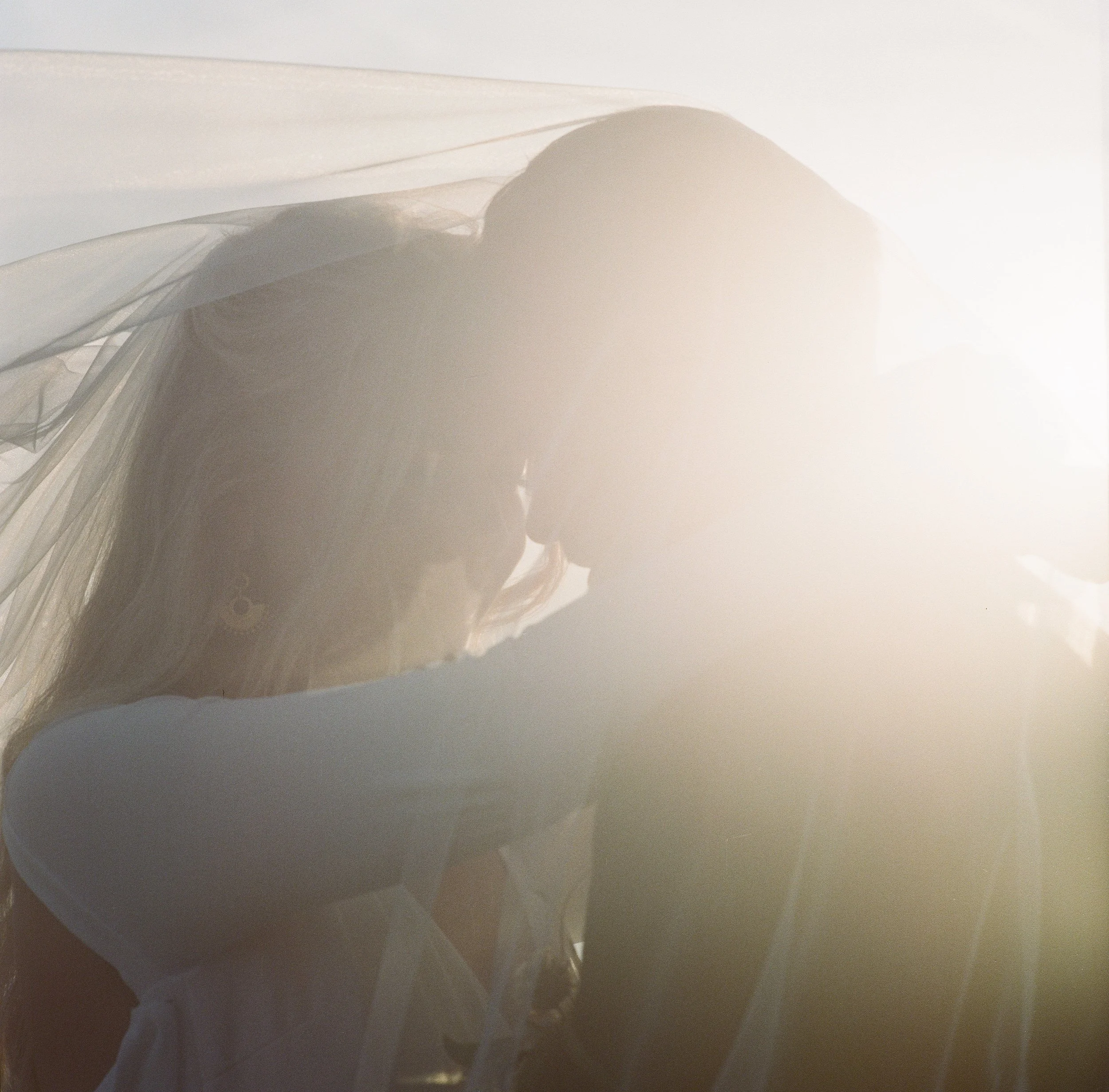 Film photography in Penzance, Cornwall of bride and groom in the hazy evening light at Marazion