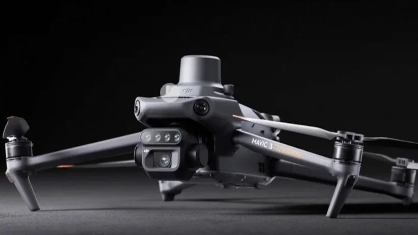 A DJI Mavic 3 drone with camera and propellers on a dark background.