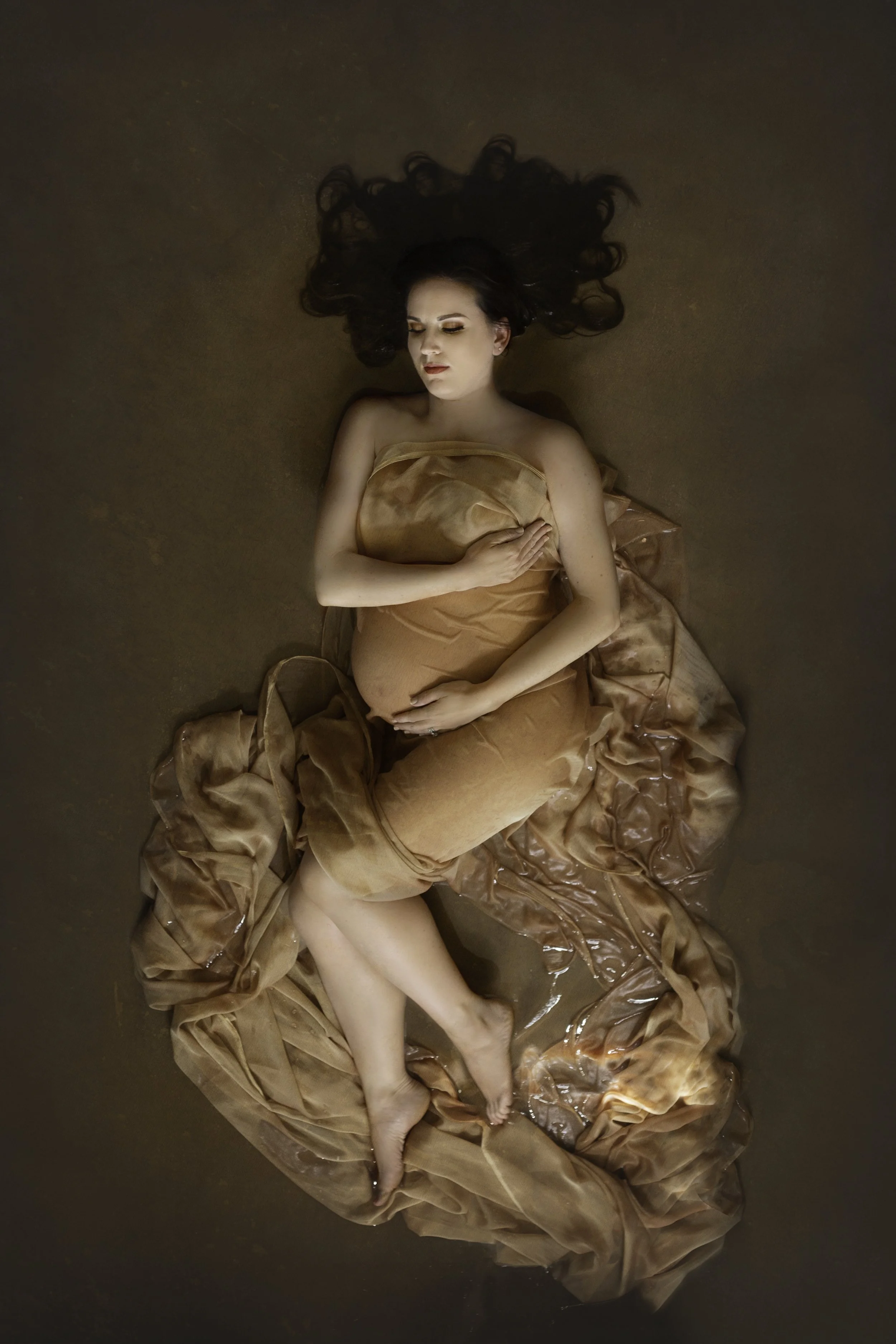 Maternity portrait, woman in gold silk in water