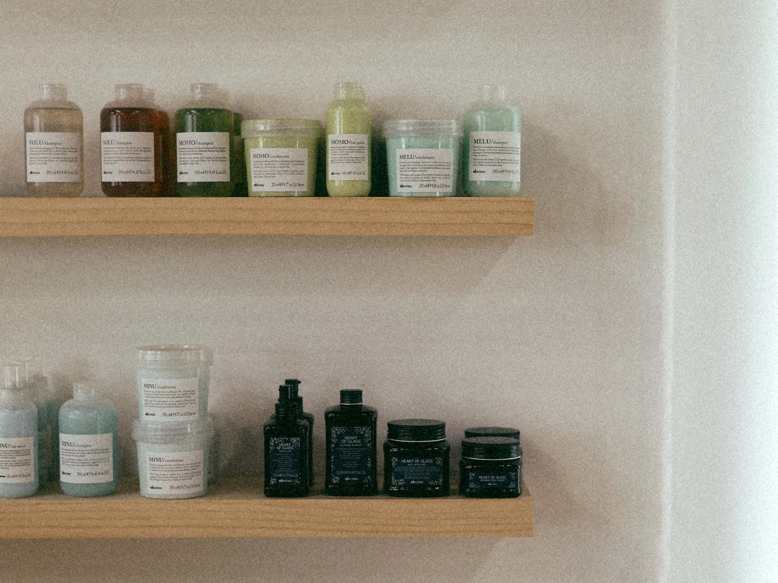 Two wooden shelves with salon hair product bottles and jars, including shampoos, conditioners, and styling products.