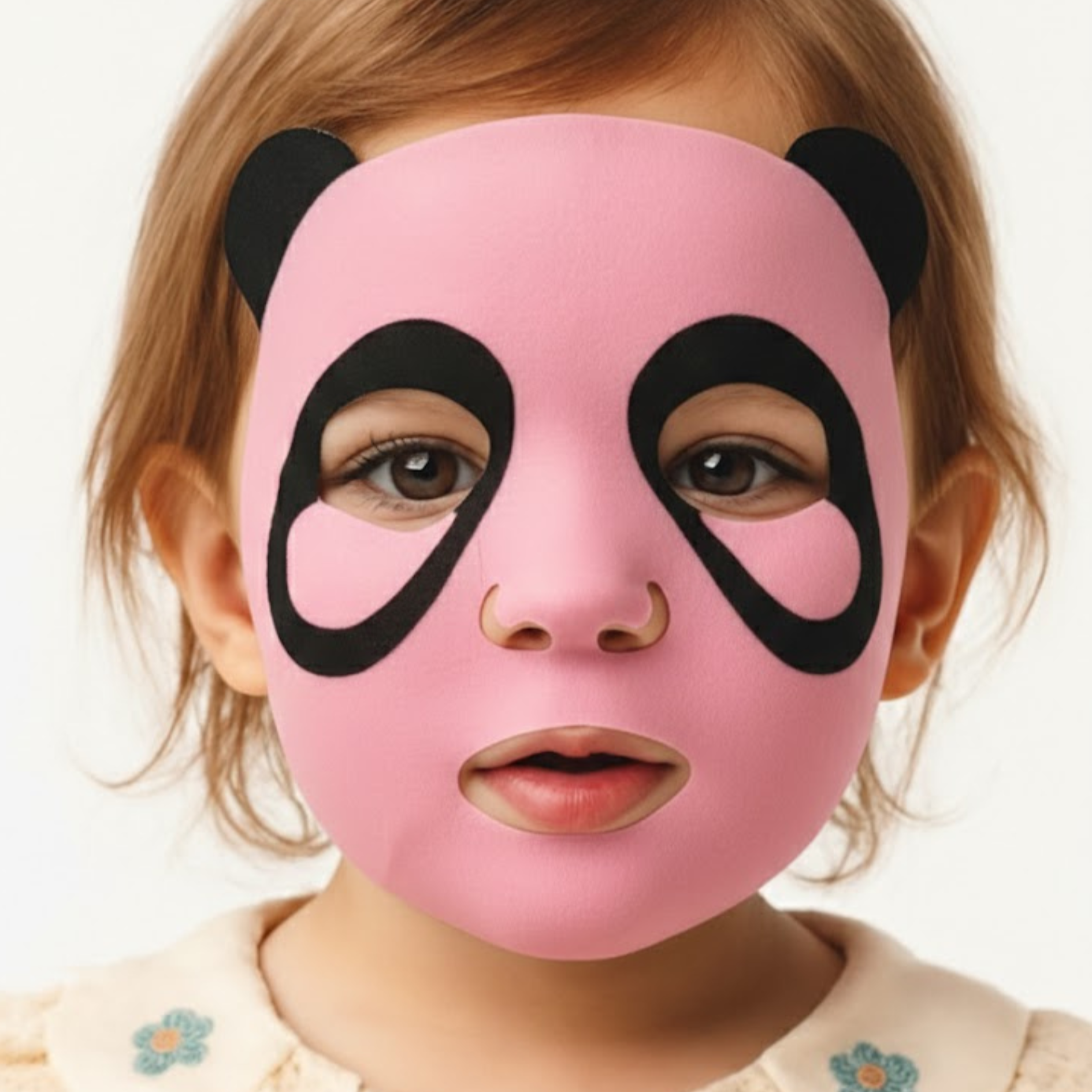 A very young child wearing a panda face mask.
