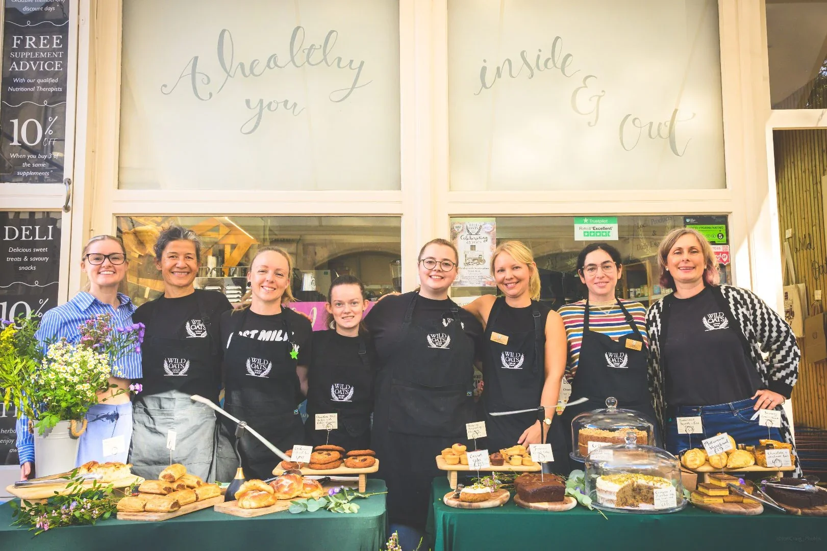 The Wild Oats team outside the store with a table of baked goods.