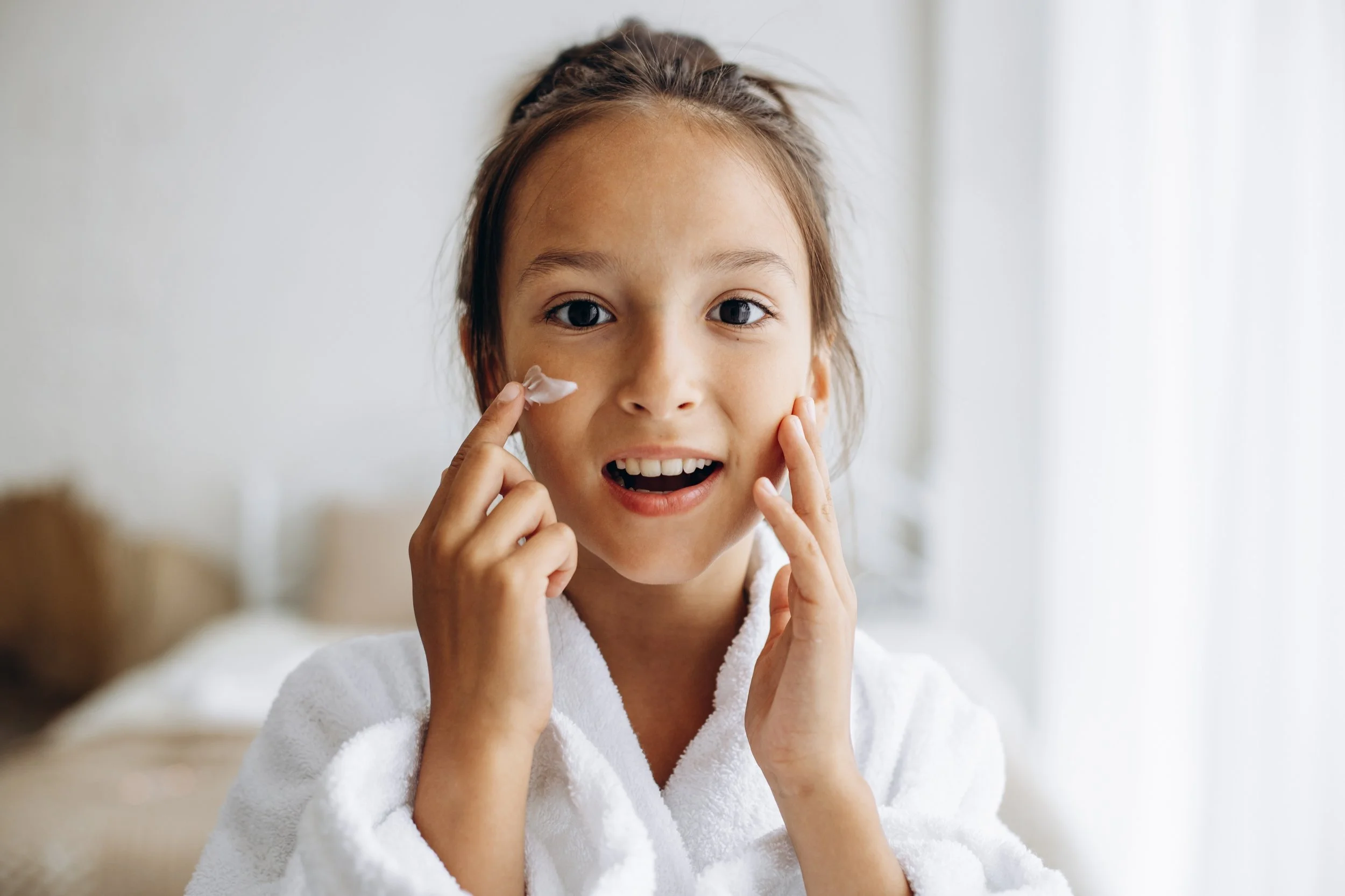 A child looks delighted as she puts lotion on her face