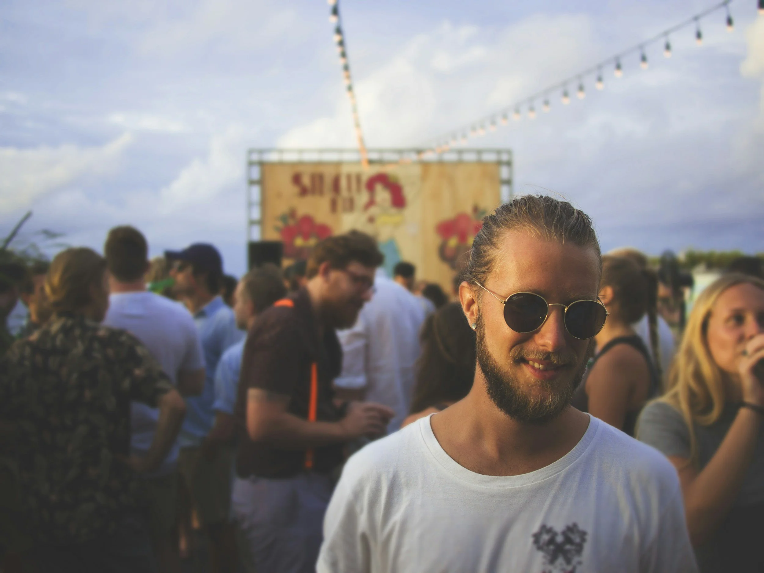 Festival goers at a music festival with a man in dark glasses looking happy in the foreground